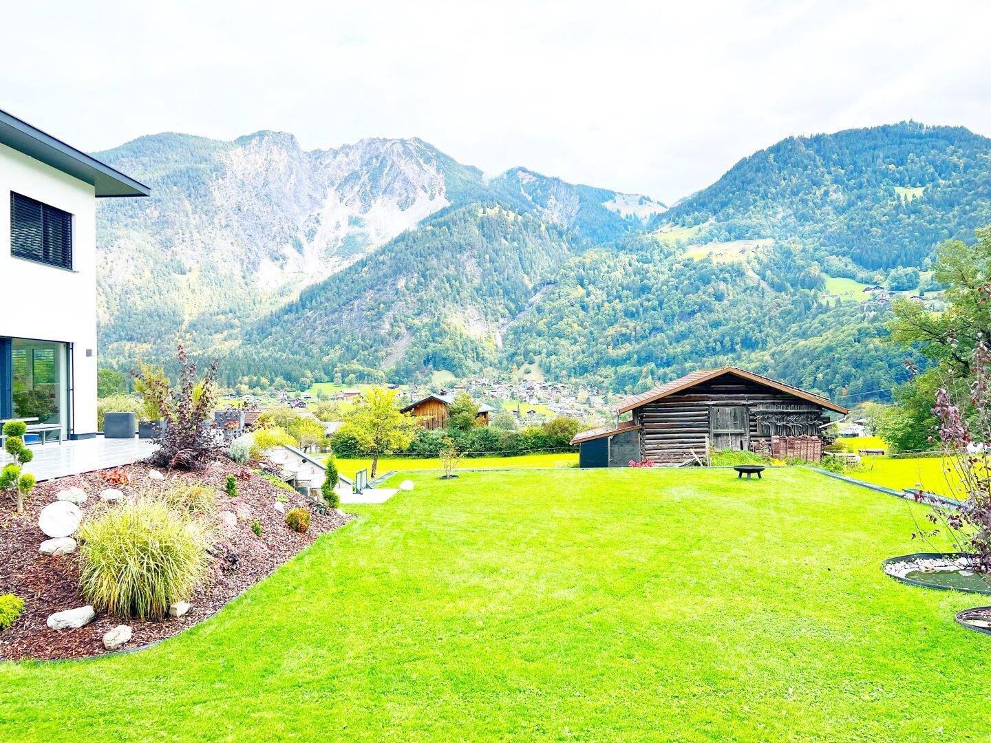 Gepflegter Gartenbereich mit Rasenfläche und beeindruckendem Panoramablick auf die Berge.