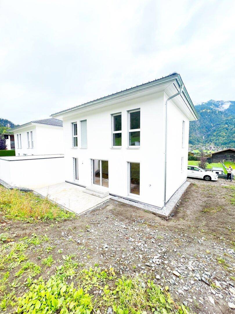 Freistehendes Einfamilienhaus mit weißer Fassade und Blick auf die umliegende Berglandschaft.