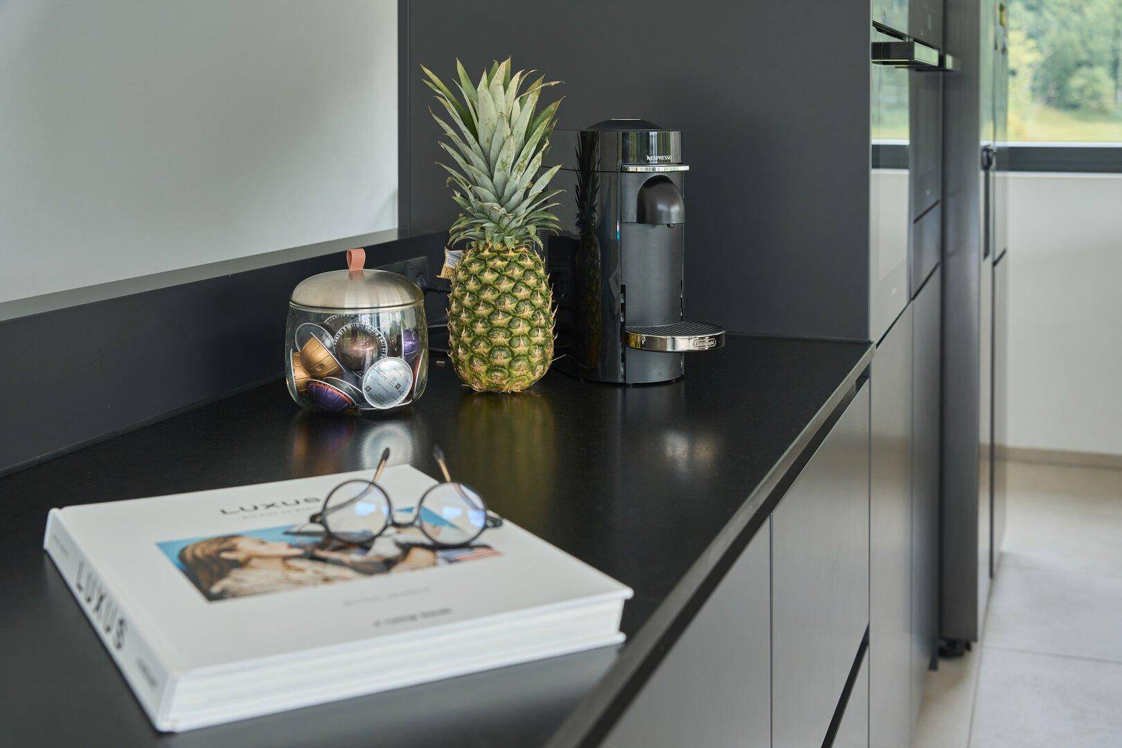 Moderne Küchenarbeitsplatte in Schwarz mit Kaffeemaschine und stilvoller Dekoration.