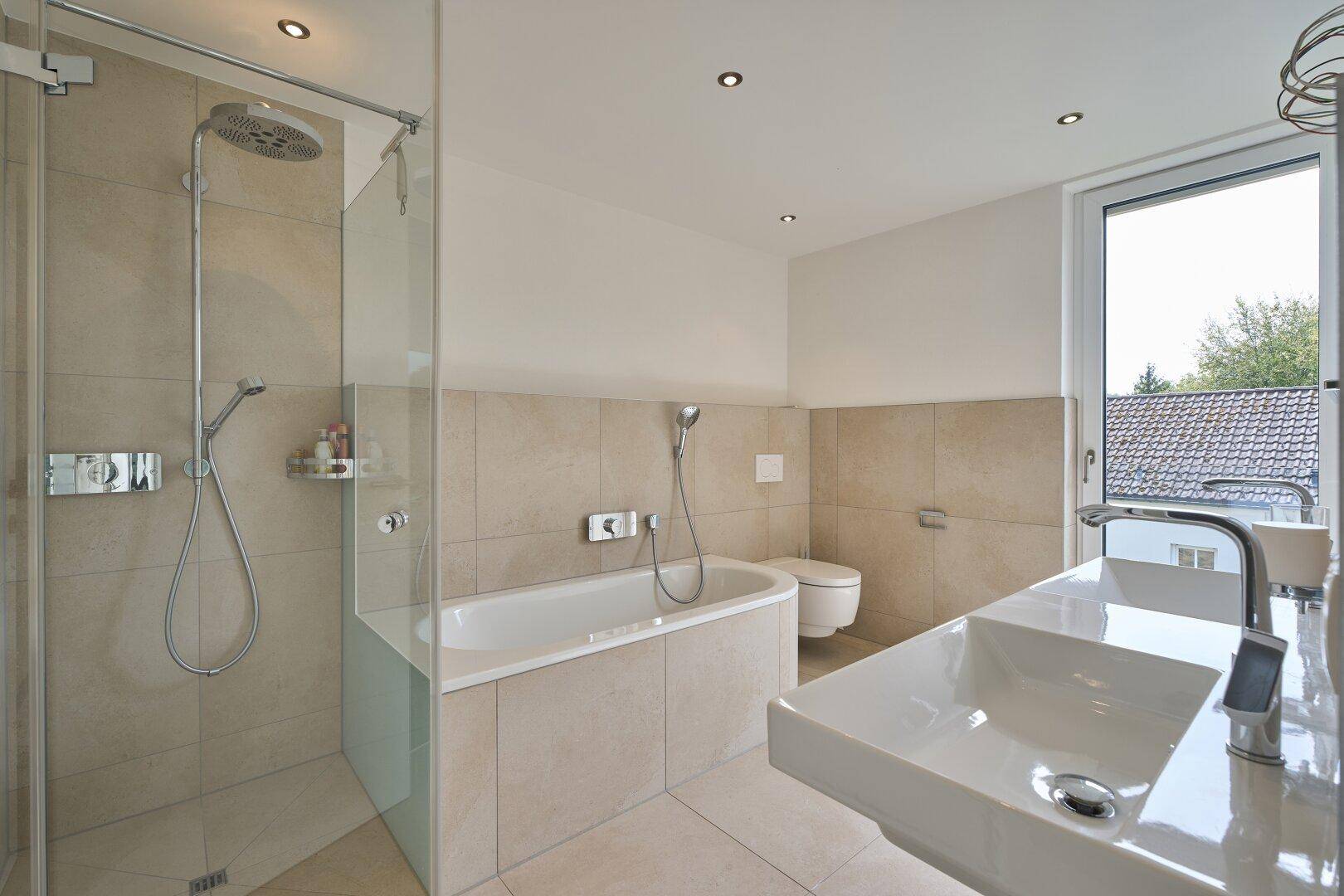 Helles Badezimmer mit Fenster, Badewanne, Dusche und modernem Waschbecken.