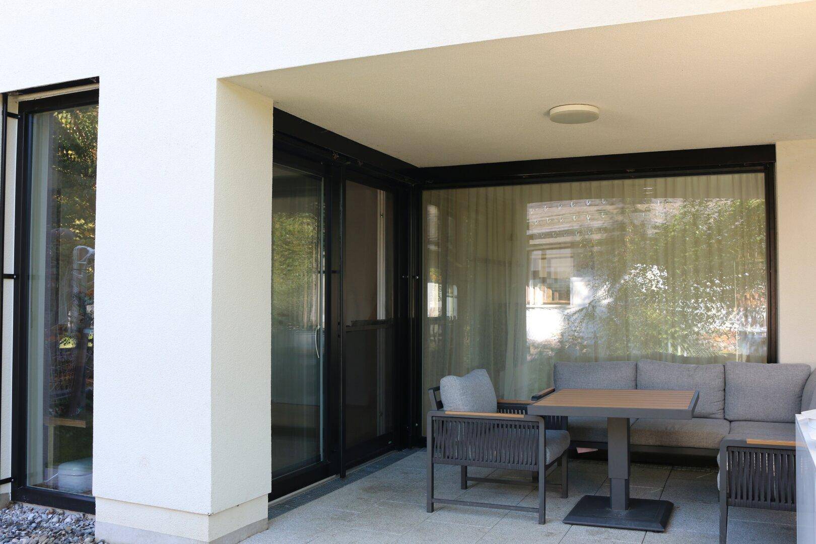 Überdachte Terrasse mit modernen Gartenmöbeln, ideal für Mahlzeiten im Freien.