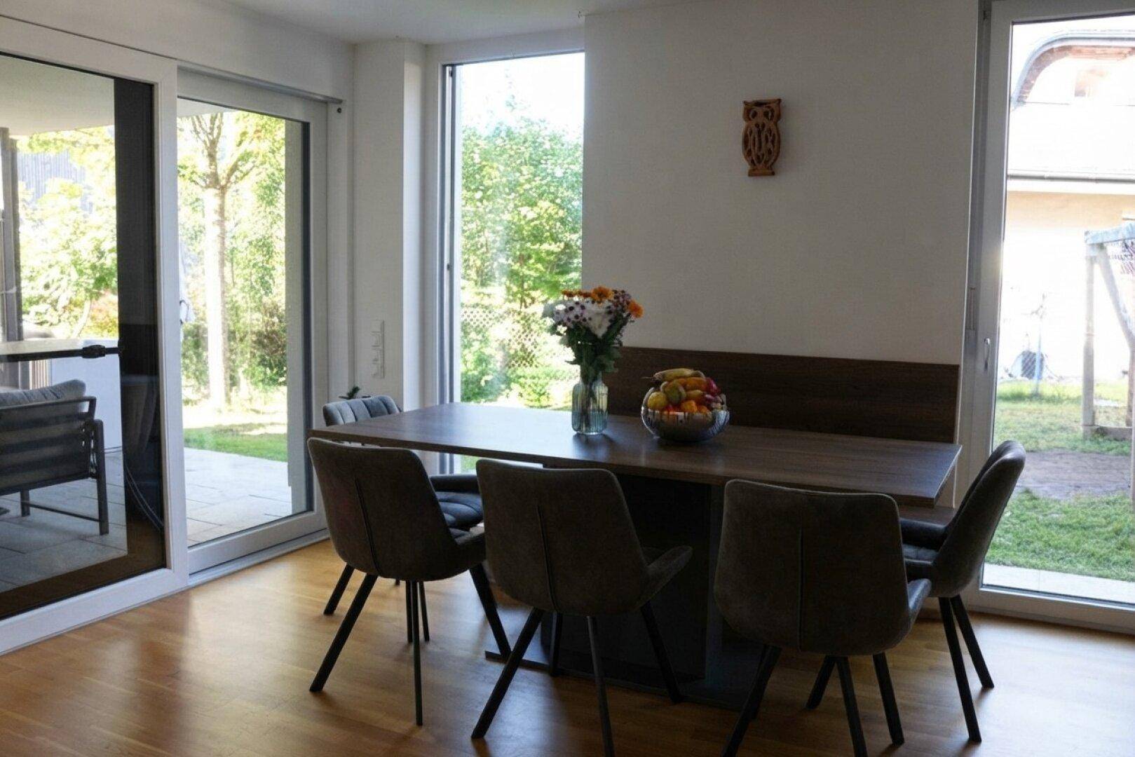 Essbereich mit Holztisch und Blick ins Grüne, ideal für Mahlzeiten mit Familie und Freunden.
