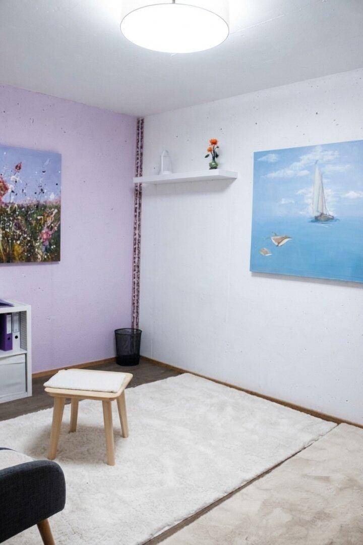 Heller Raum mit farbigen Wänden, Teppichboden und Kunstwerken an den Wänden.