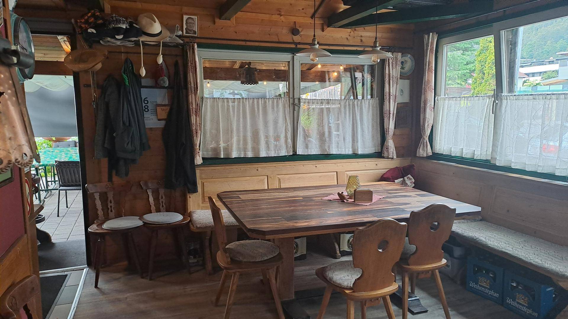 Gemütlicher Essbereich im Landhausstil mit Holzwänden, rustikalen Möbeln und Fenstern, die viel Tageslicht hereinlassen.