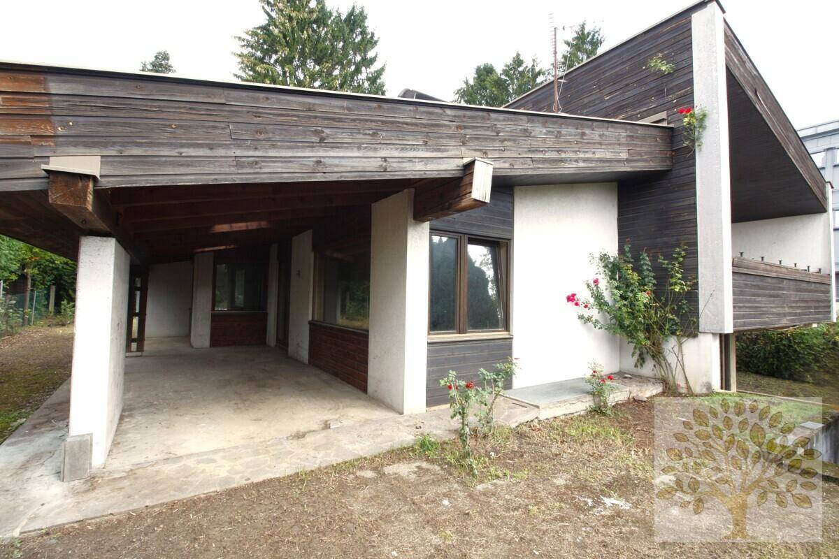 Seitlicher Blick auf das Haus mit überdachtem Carport und Holzfassade.