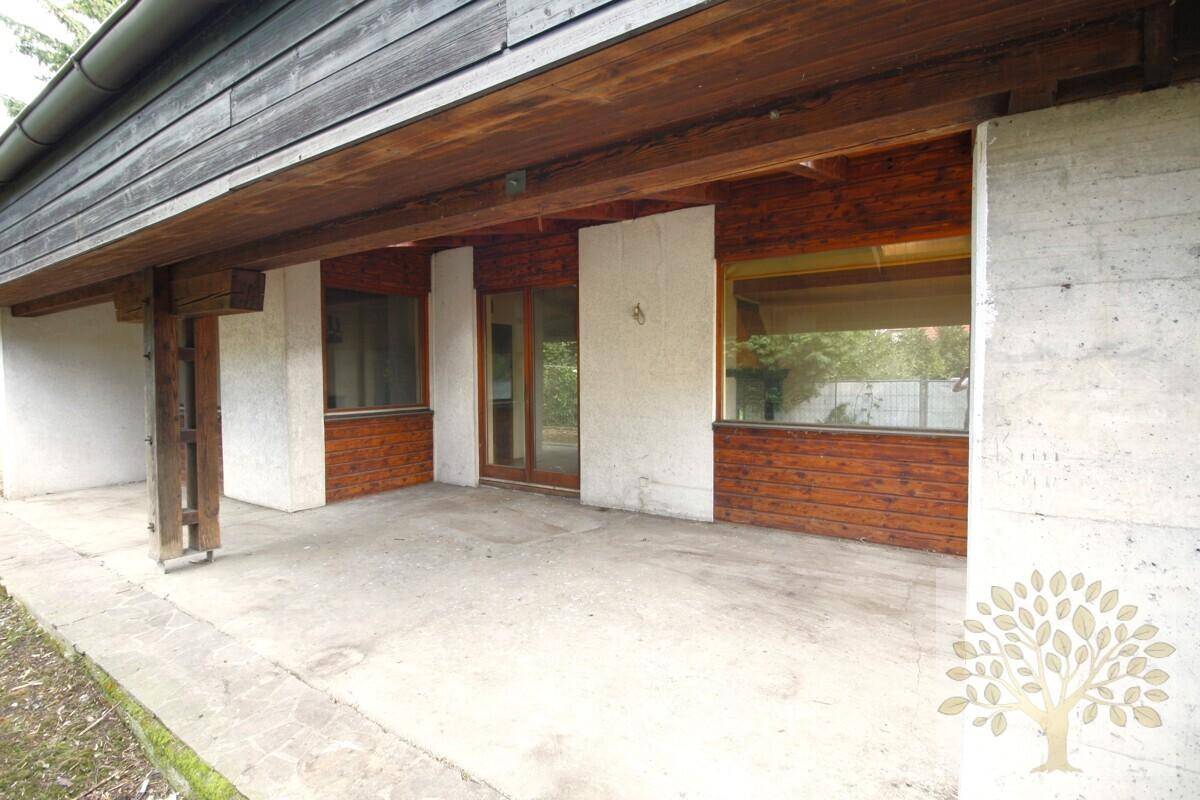 Überdachte Terrasse mit Betonboden und Holzbalken, ideal für entspannte Stunden im Freien.