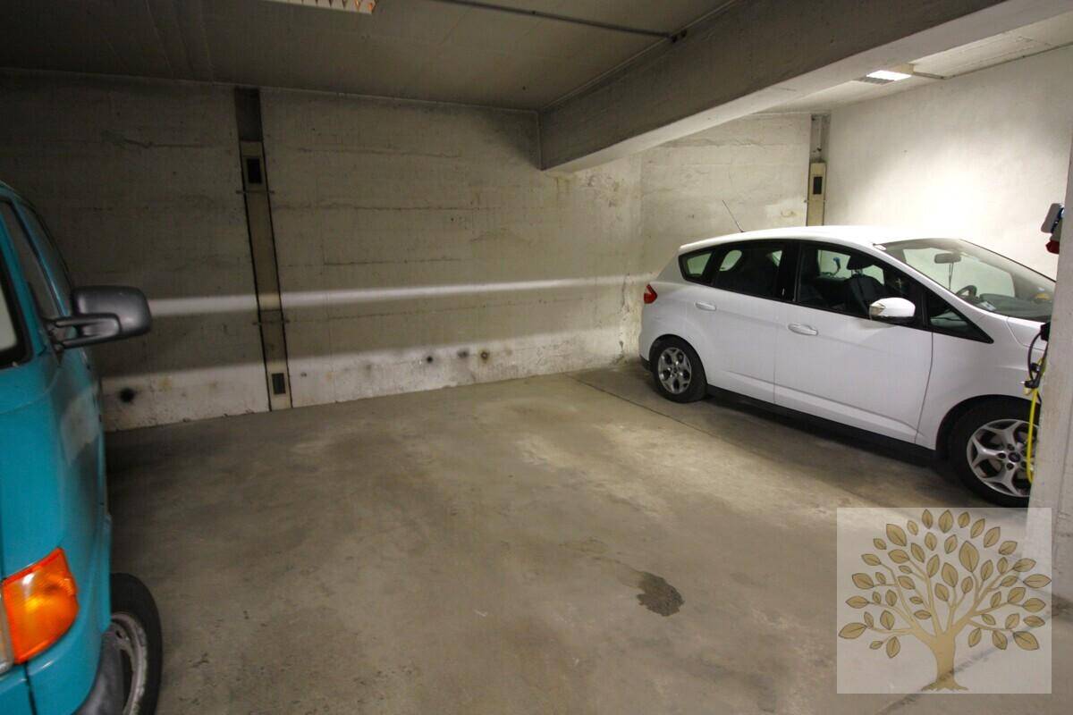 Einzelner Stellplatz in der Tiefgarage, umgeben von Betonwänden und mit einem weißen Auto geparkt.