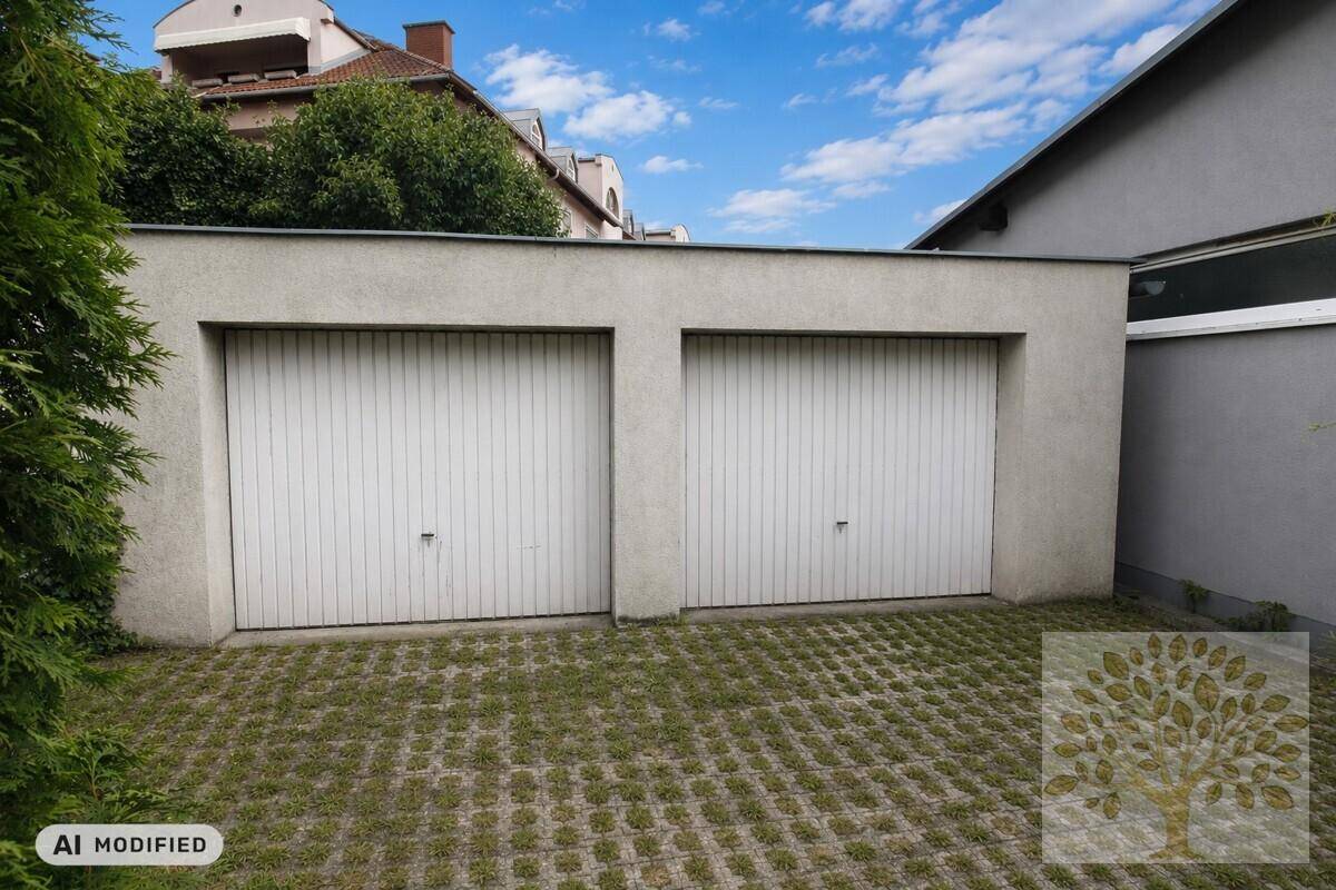 Doppelgarage mit zwei weißen Toren und Rasengittersteinen im Vordergrund.