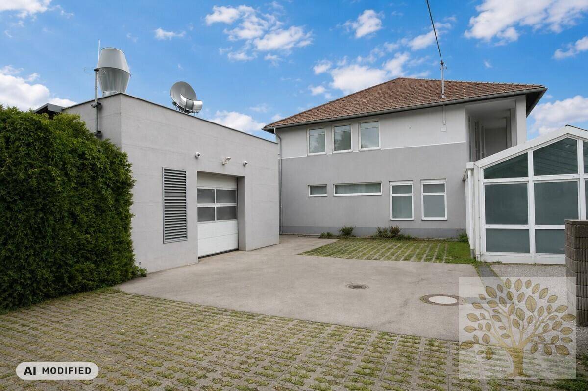 Rückansicht des Hauses mit Einfahrt, Rasengittersteinen und einem Garagentor.