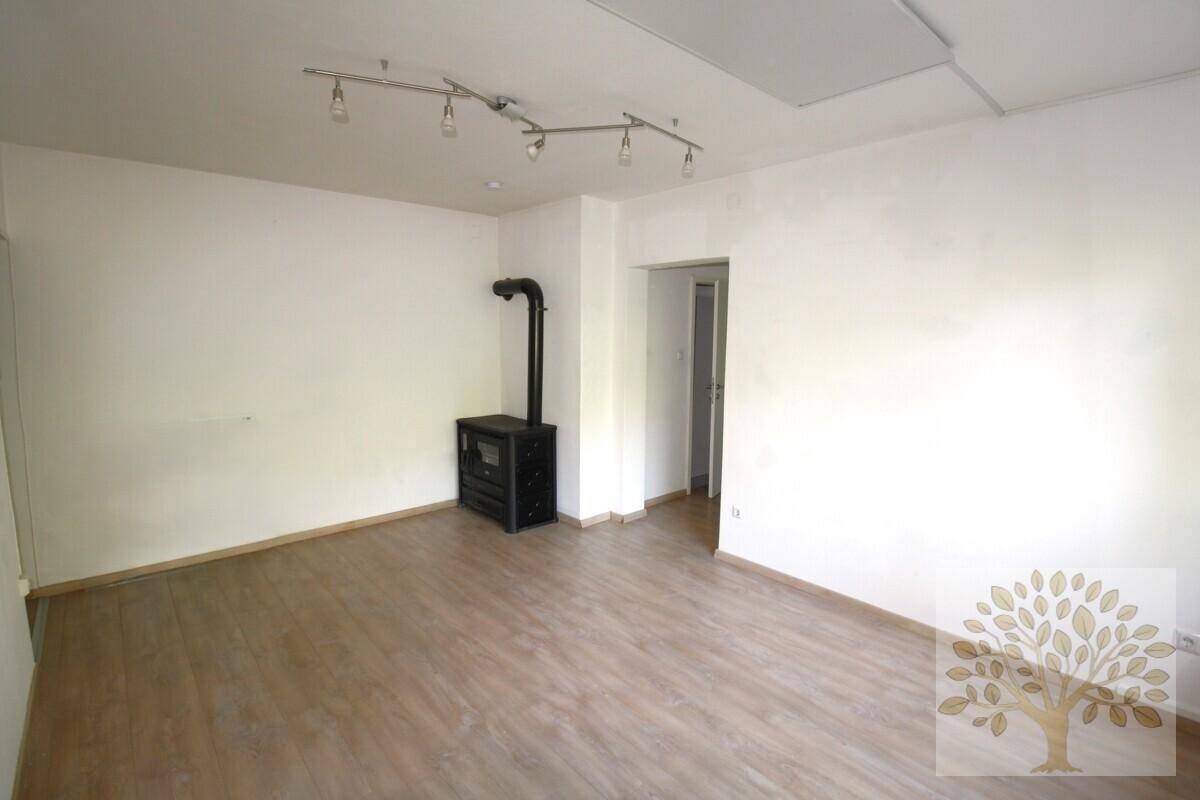 Geräumiges Zimmer mit Laminatboden und einem modernen Holzofen als Heizquelle.
