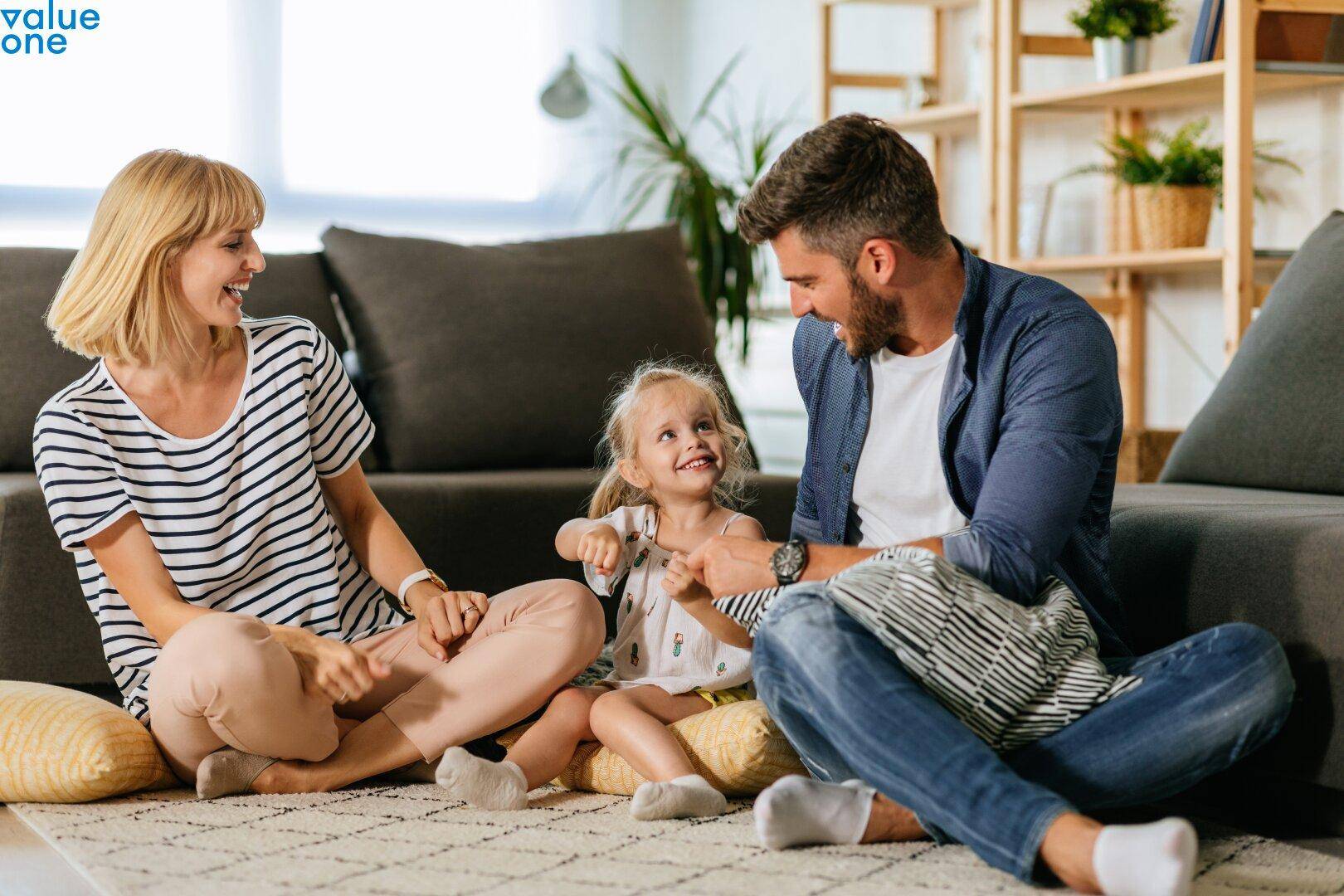 Gemütliches Wohnzimmer mit einer Familie, die auf dem Teppichboden spielt und moderner Dekoration.