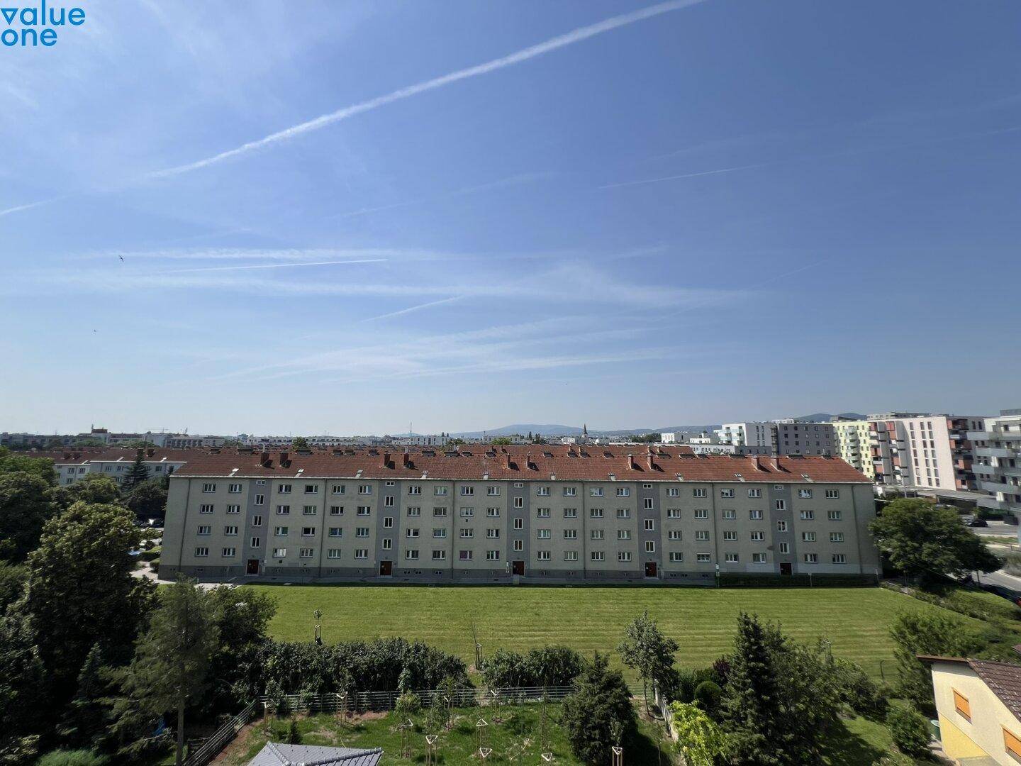 Weitläufige Ansicht eines Wohngebäudes mit großer Grünfläche und klarem Himmel.