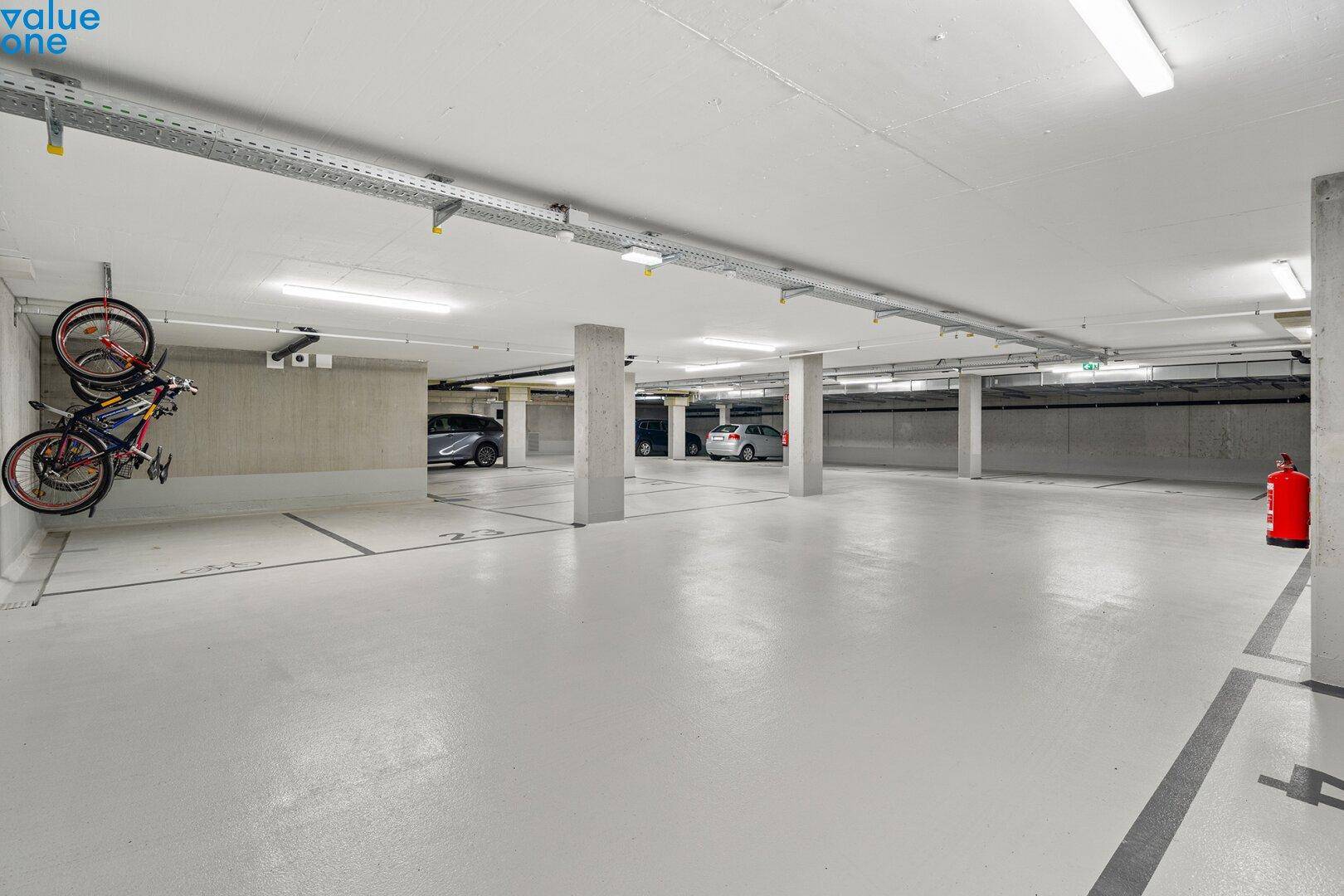 Geräumige Tiefgarage mit Betonpfeilern, markierten Stellplätzen und Fahrradaufhängungen an der Wand.