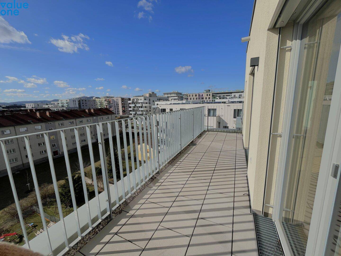Heller Balkon mit Fliesenboden und weitem Blick über die Stadt.