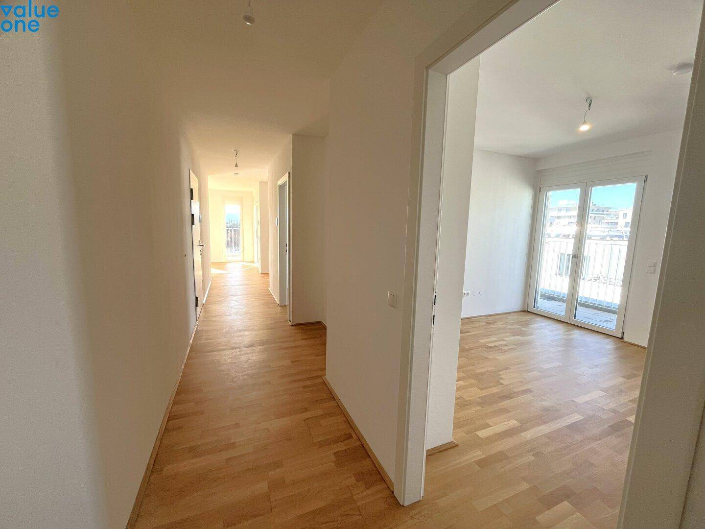 Langer, heller Flur mit Parkettboden und Zugang zu verschiedenen Räumen.