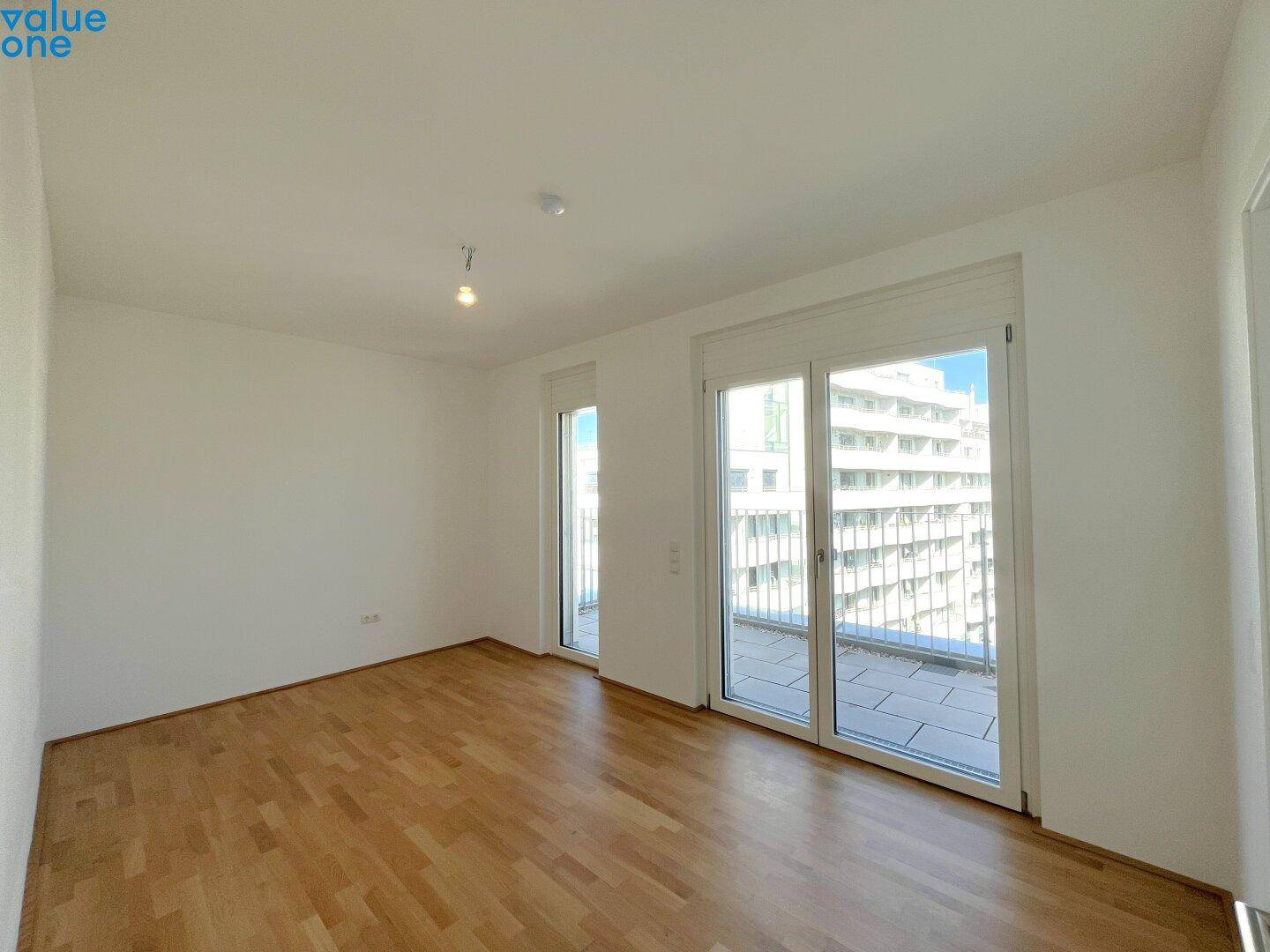 Lichtdurchflutetes Schlafzimmer mit Parkettboden und großem Fenster zur Terrasse.