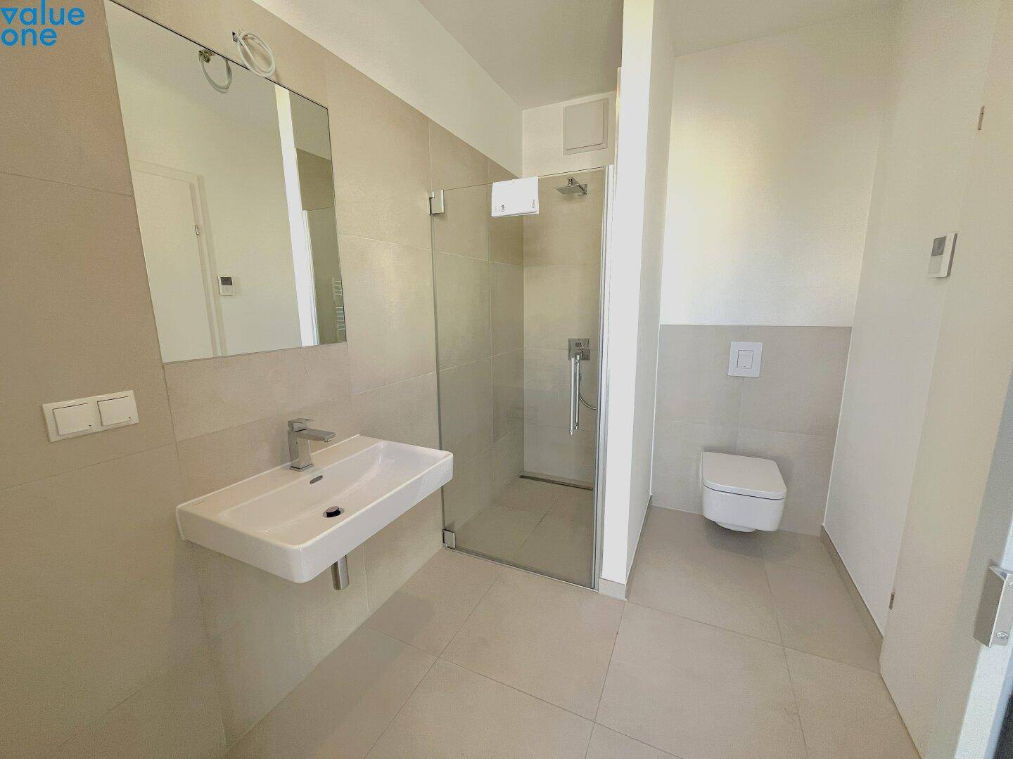 Modernes Badezimmer mit begehbarer Dusche, Wand-WC und großem Spiegel.