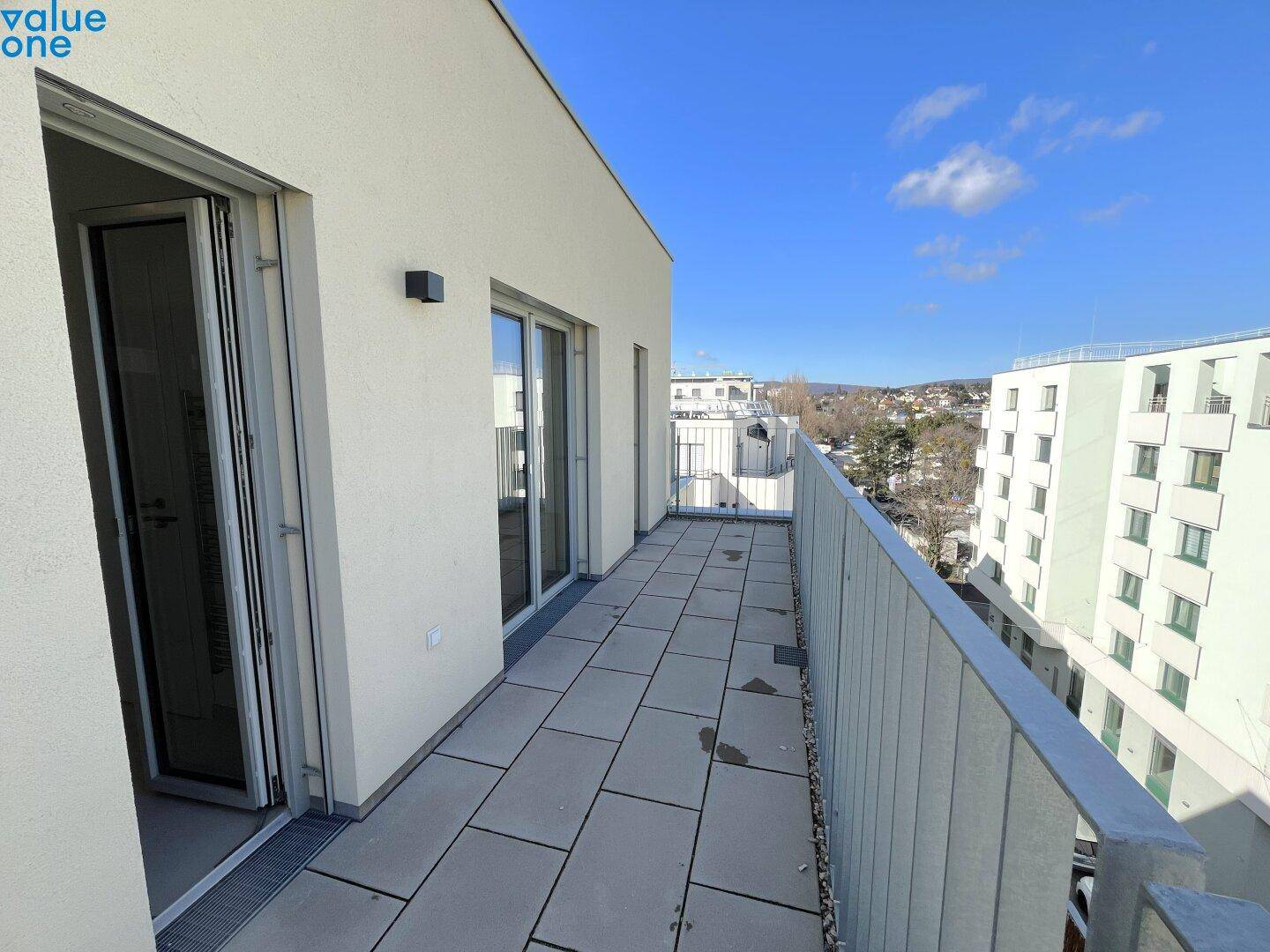Langer, schmaler Balkon mit Fliesenboden und Blick auf die Umgebung.