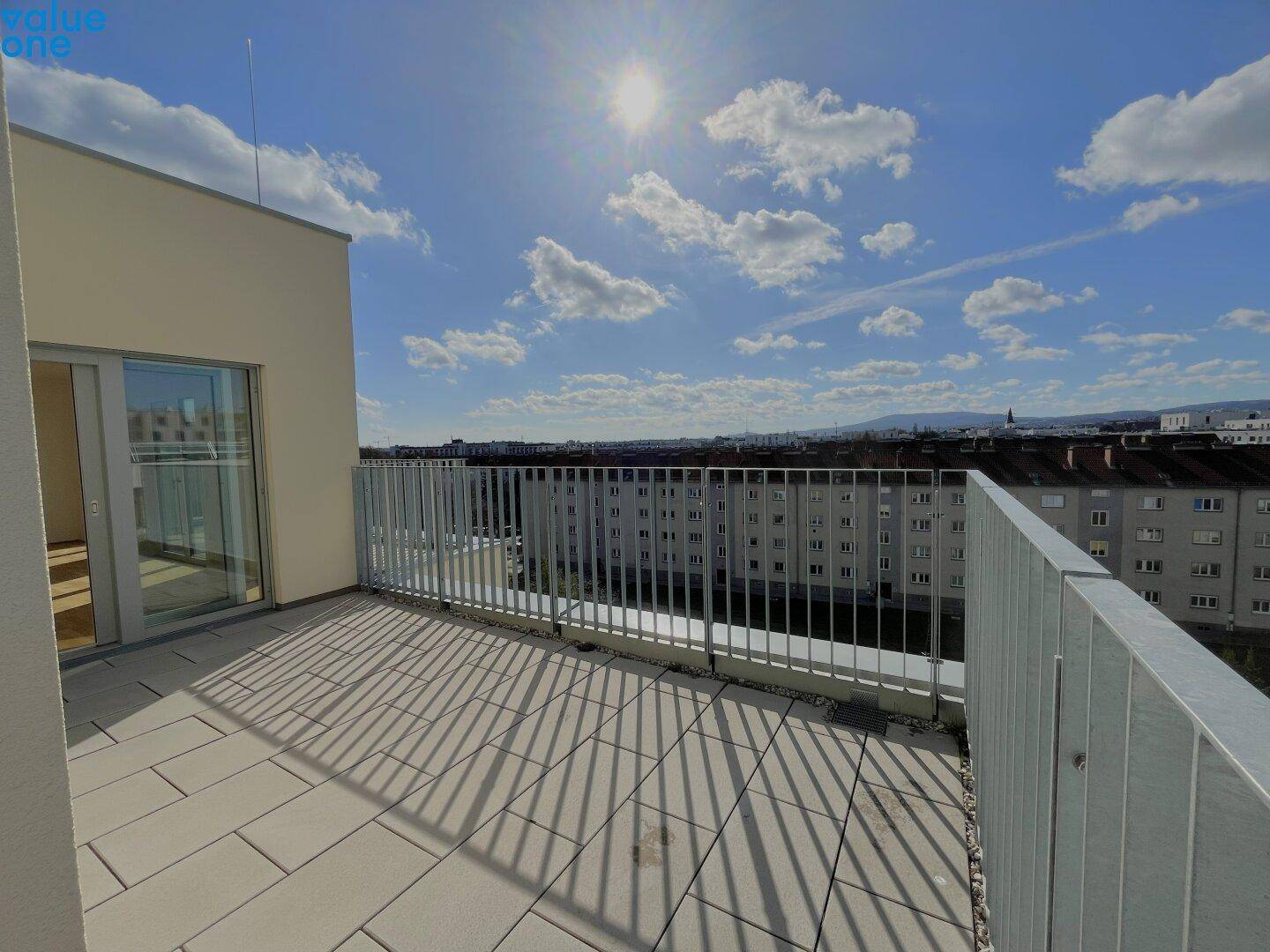 Große, sonnige Dachterrasse mit Fliesenboden und weitem Blick über die Stadt.