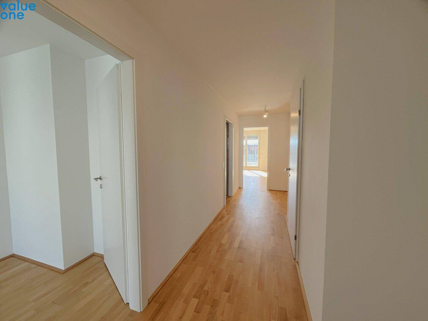 Heller Flur mit Holzboden und mehreren Türen, der zu weiteren Räumen der Wohnung führt.