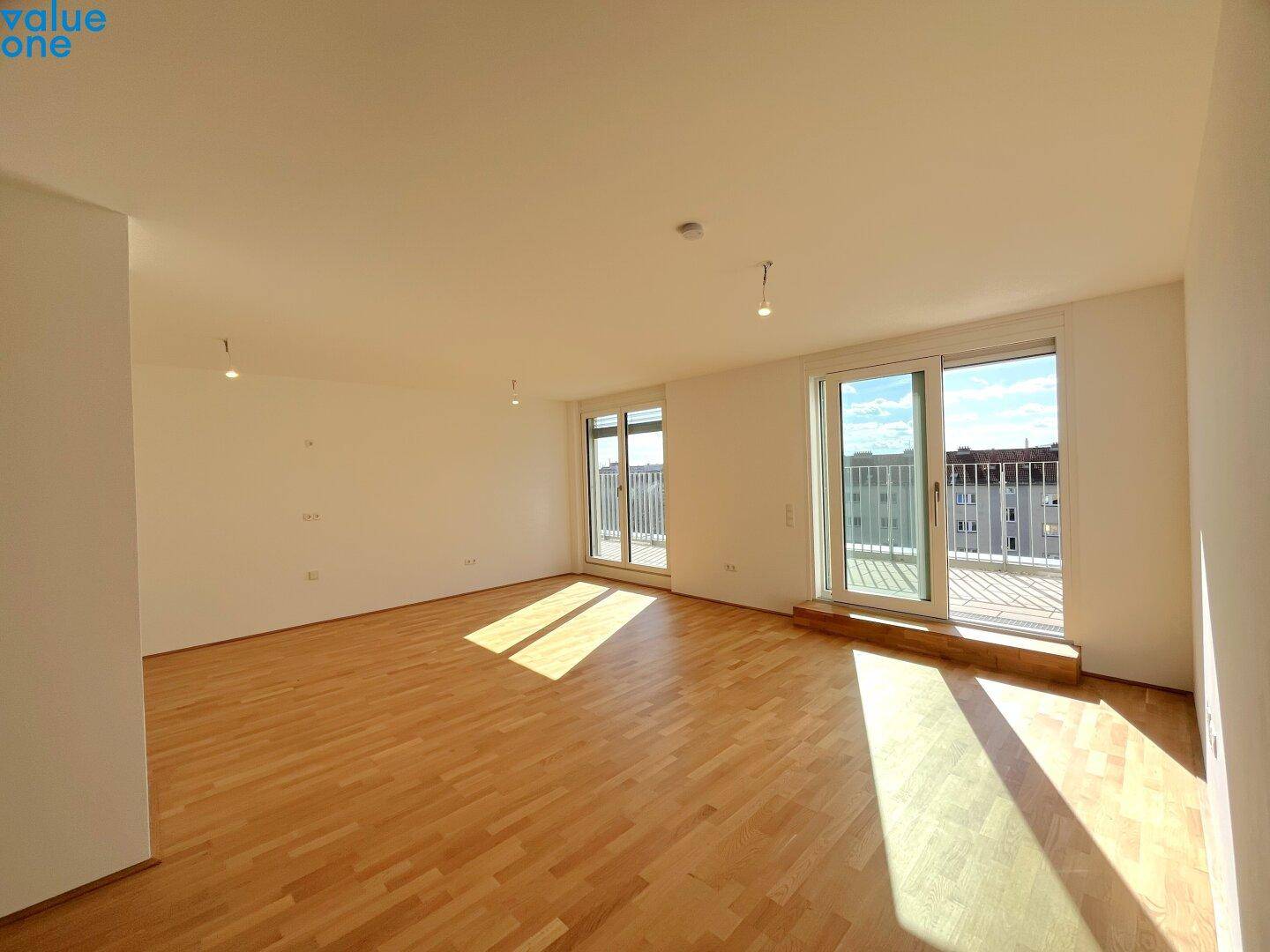 Geräumiger, heller Wohnbereich mit Holzboden und großen Schiebetüren zum Balkon, ideal für sonnige Tage.
