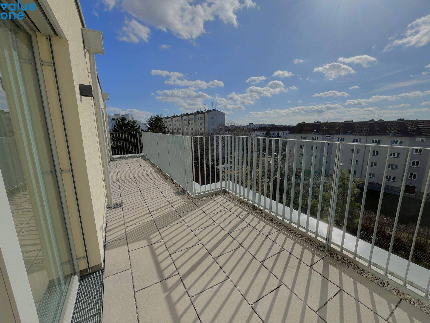 Großer, sonniger Balkon mit Fliesenboden und Metallgeländer, bietet einen weiten Blick über die Stadt.