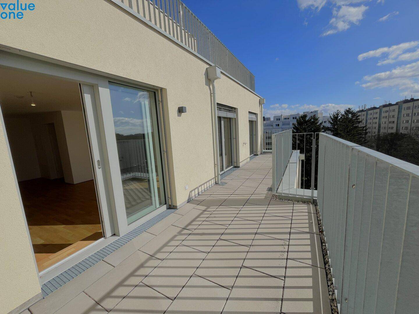 Langer Balkon mit Fliesenboden und Zugang von mehreren Räumen, ideal für Entspannung im Freien.