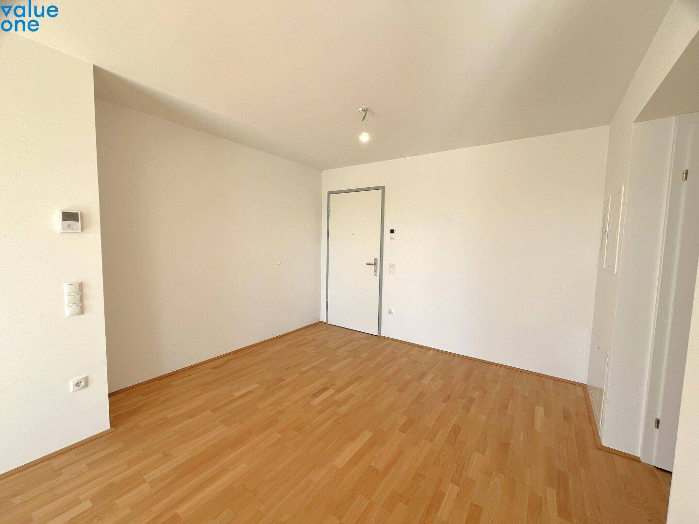 Leeres Zimmer mit Holzboden und weiß gestrichenen Wänden, bereit für individuelle Einrichtung.
