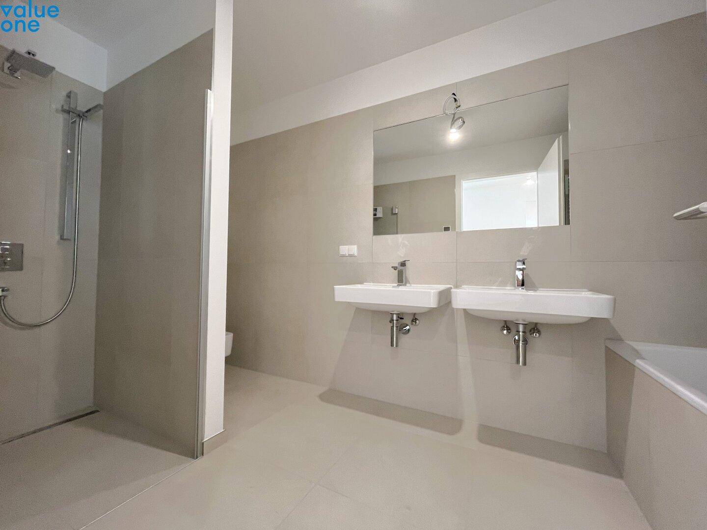 Modernes Badezimmer mit Doppelwaschbecken, großer Dusche und Badewanne, in hellen Fliesen gehalten.