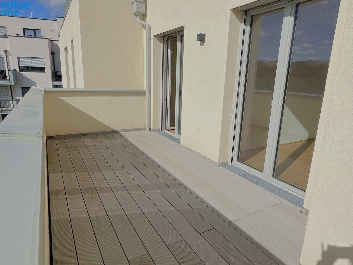 Geräumiger Balkon mit Holzdielenboden und Blick auf die umliegenden Gebäude.