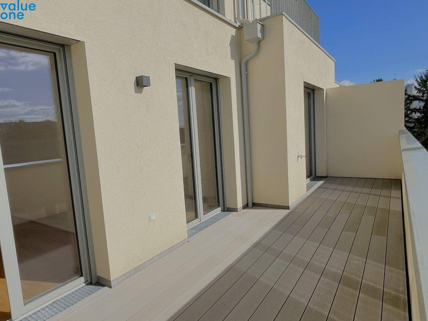 Langer Balkon mit modernem Dielenboden und Zugang durch mehrere Fenstertüren.