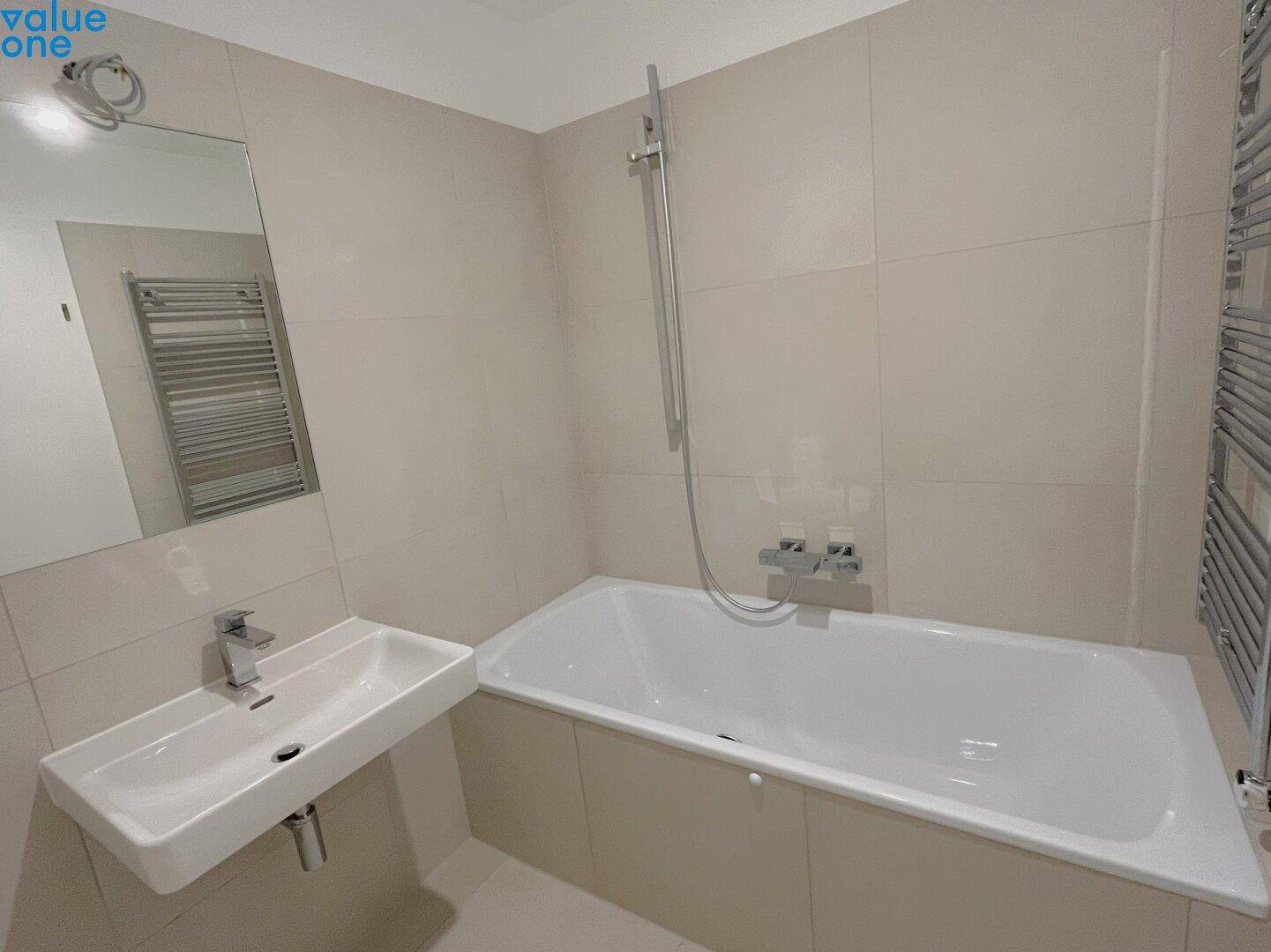 Helles Badezimmer mit Badewanne, Duschfunktion und modernem Waschbecken.