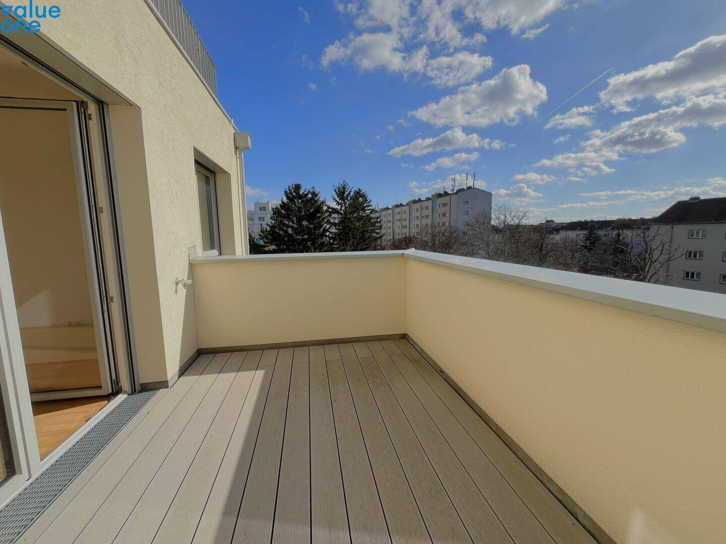 Heller, leerer Balkon mit Holzdielenboden und weitem Blick auf die Stadt.