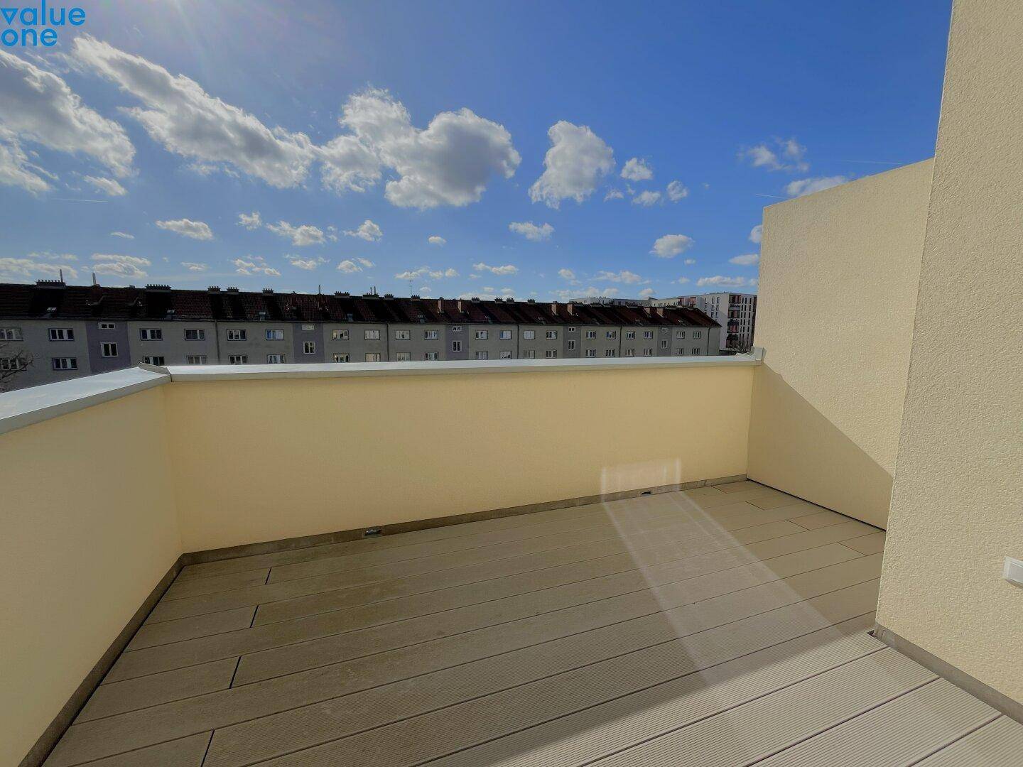 Heller, leerer Balkon mit Holzdielenboden und weitem Blick auf die Stadt.