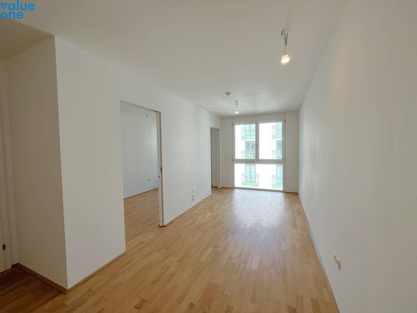 Geräumiger, heller Wohnraum mit Parkettboden und großen Fenstern, ideal für individuelle Einrichtung.