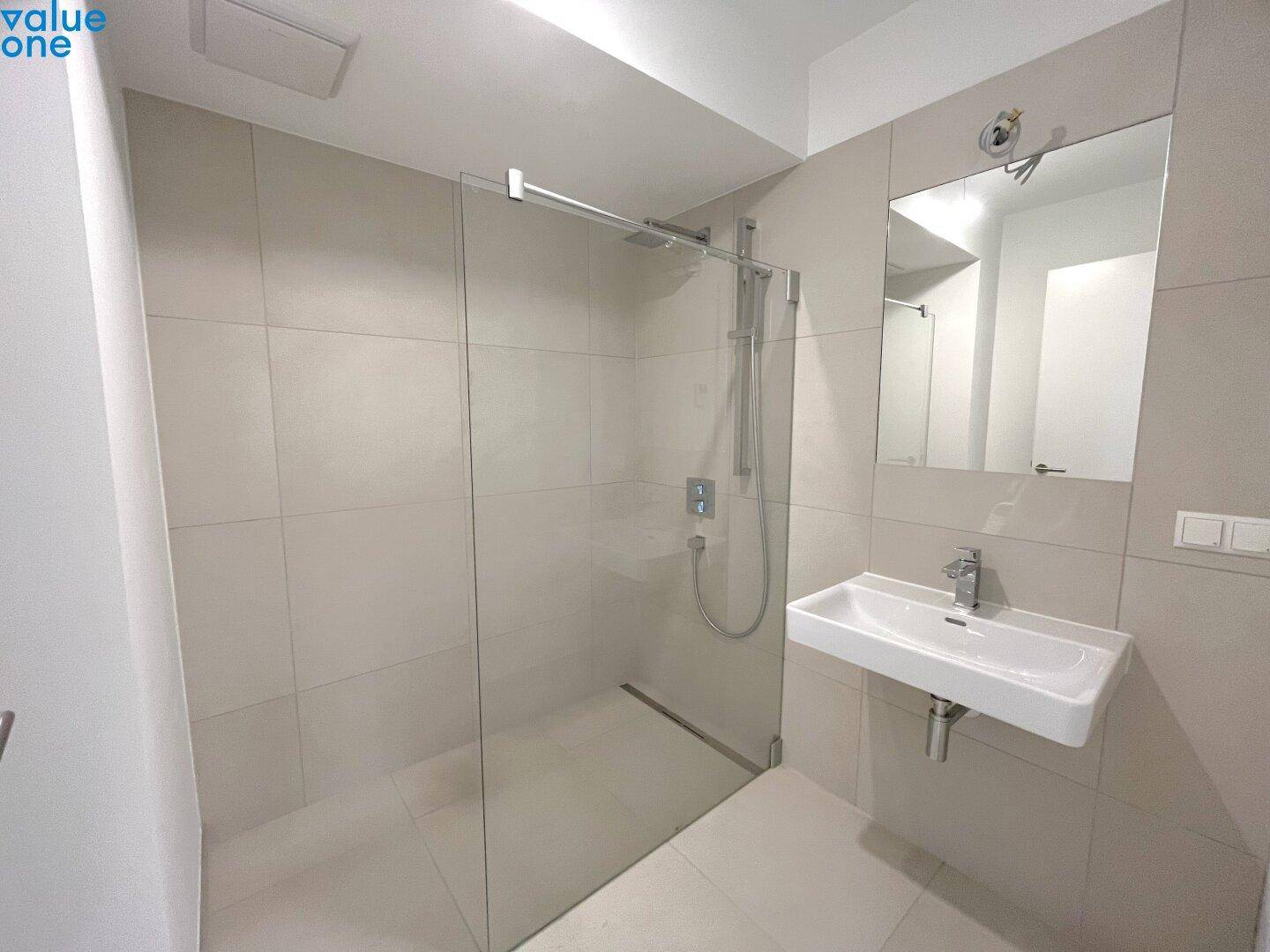 Helles Badezimmer mit großer begehbarer Dusche und modernen, hellen Fliesen.