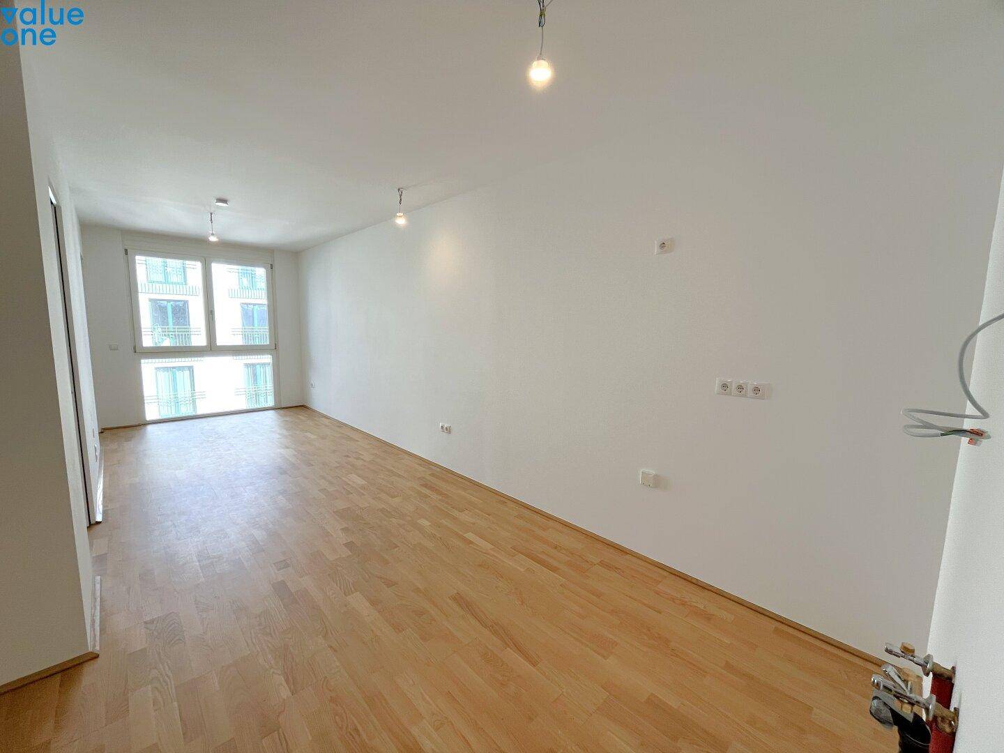 Geräumiger, heller Wohnraum mit Parkettboden und großen Fenstern, bereit zur individuellen Gestaltung.