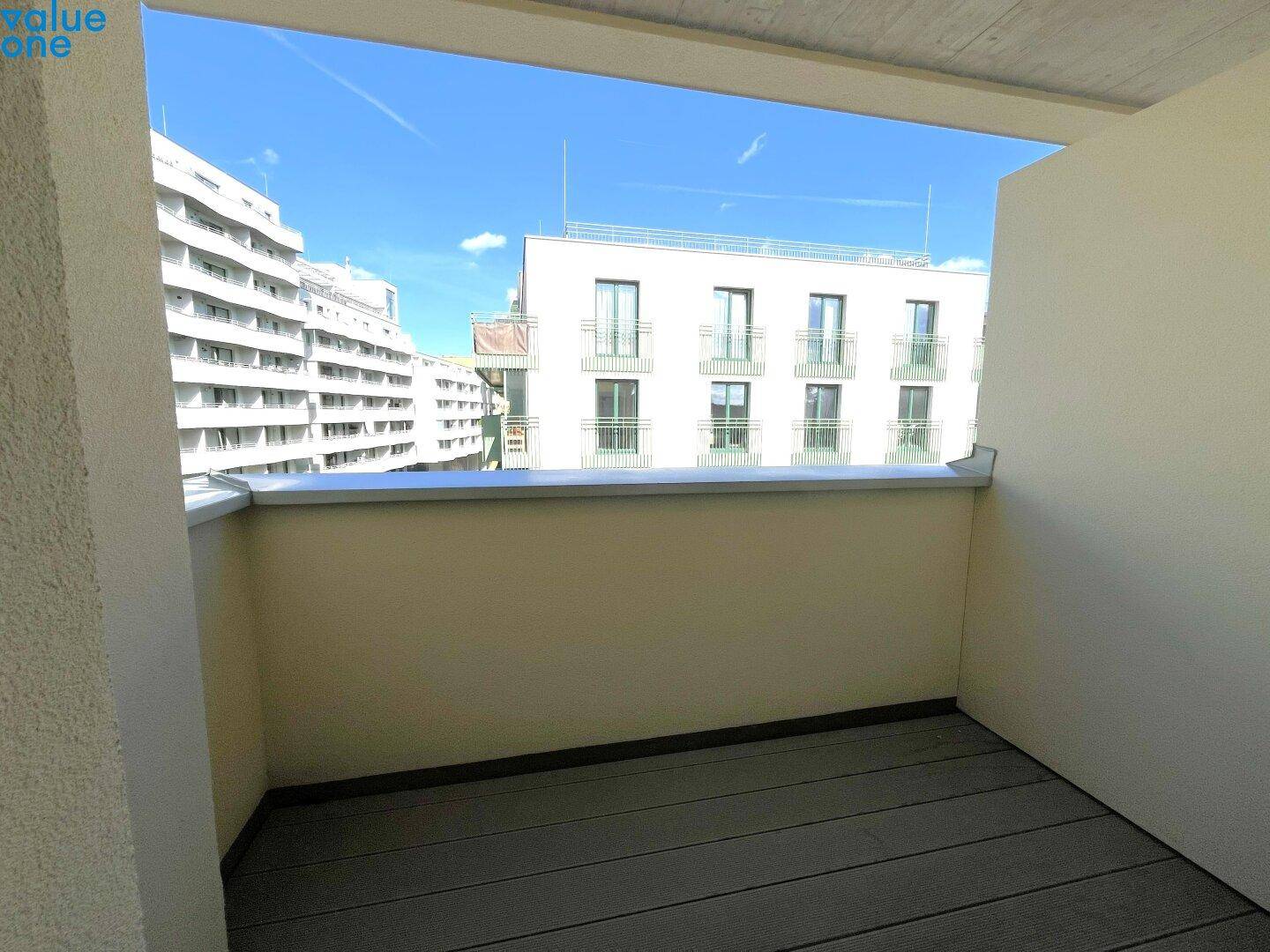 Geräumiger Balkon mit Holzdielenboden und freiem Blick auf die städtische Umgebung.