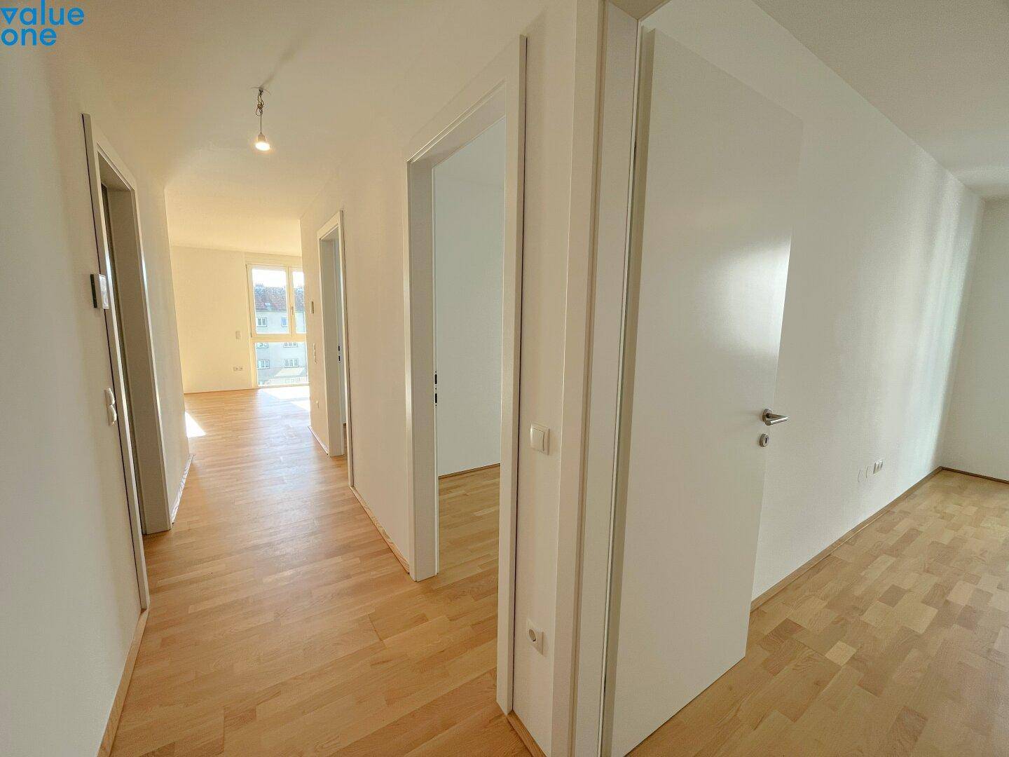 Heller Flur mit Holzboden, der zu verschiedenen Räumen der Wohnung führt.
