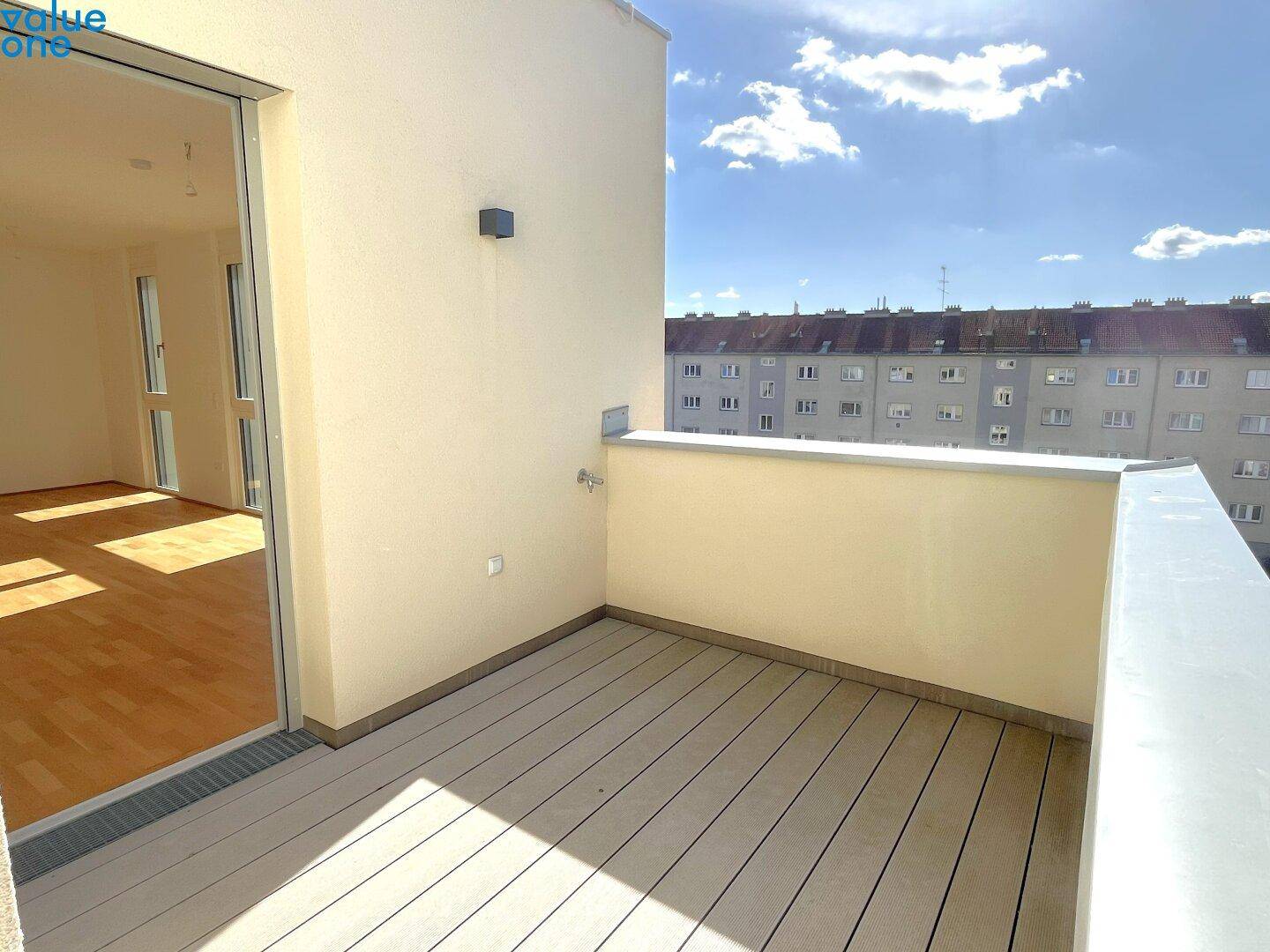 Geräumiger Balkon mit Holzdielenboden und Blick auf die umliegenden Gebäude.