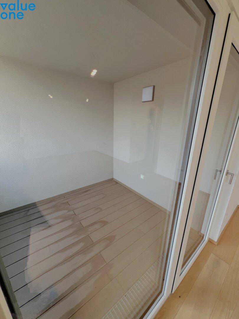 Helle Loggia mit Holzbodenoptik, ideal für entspannte Stunden im Freien.