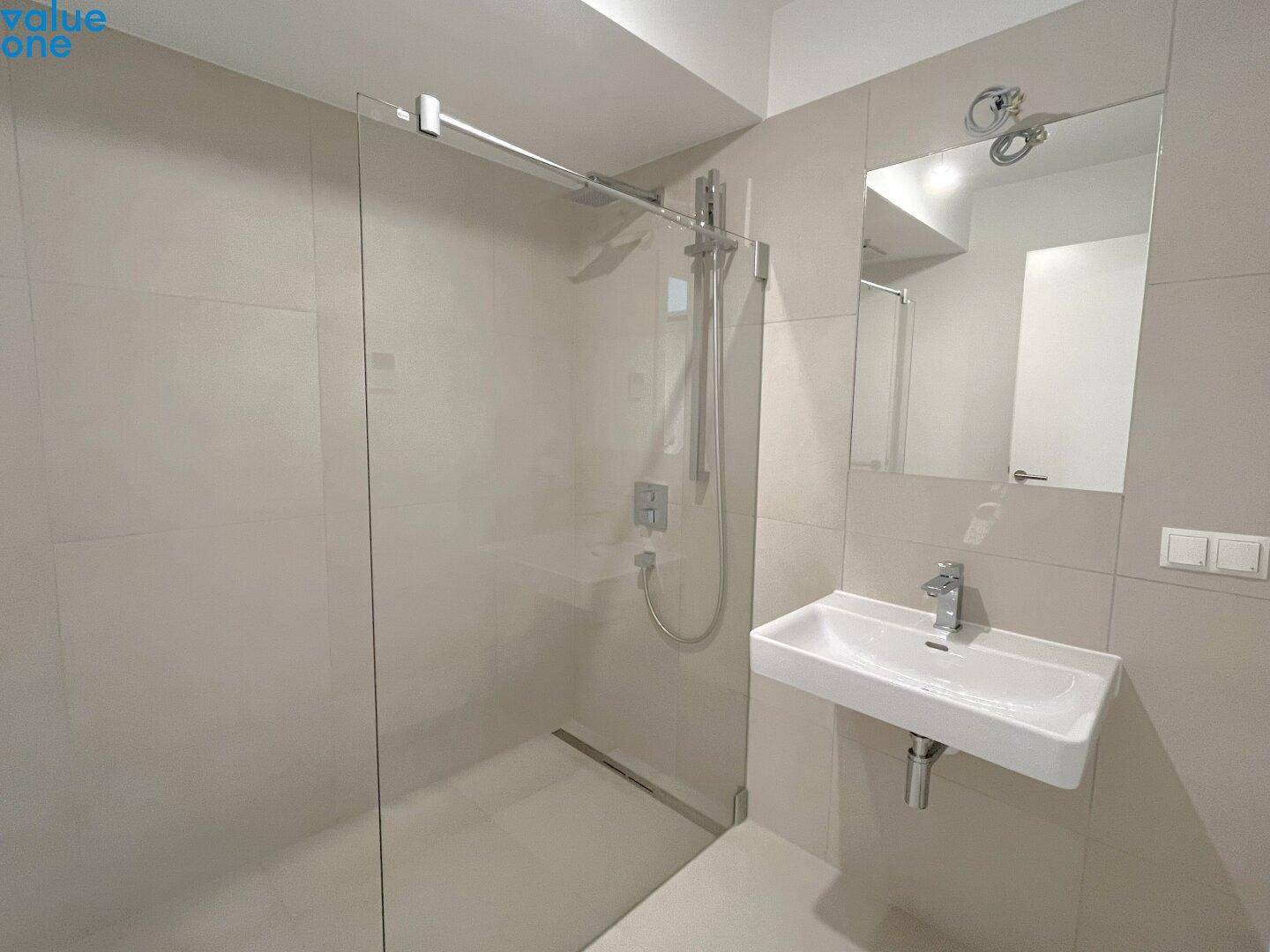 Modernes Badezimmer mit ebenerdiger Dusche, Waschbecken und hellen Fliesen.