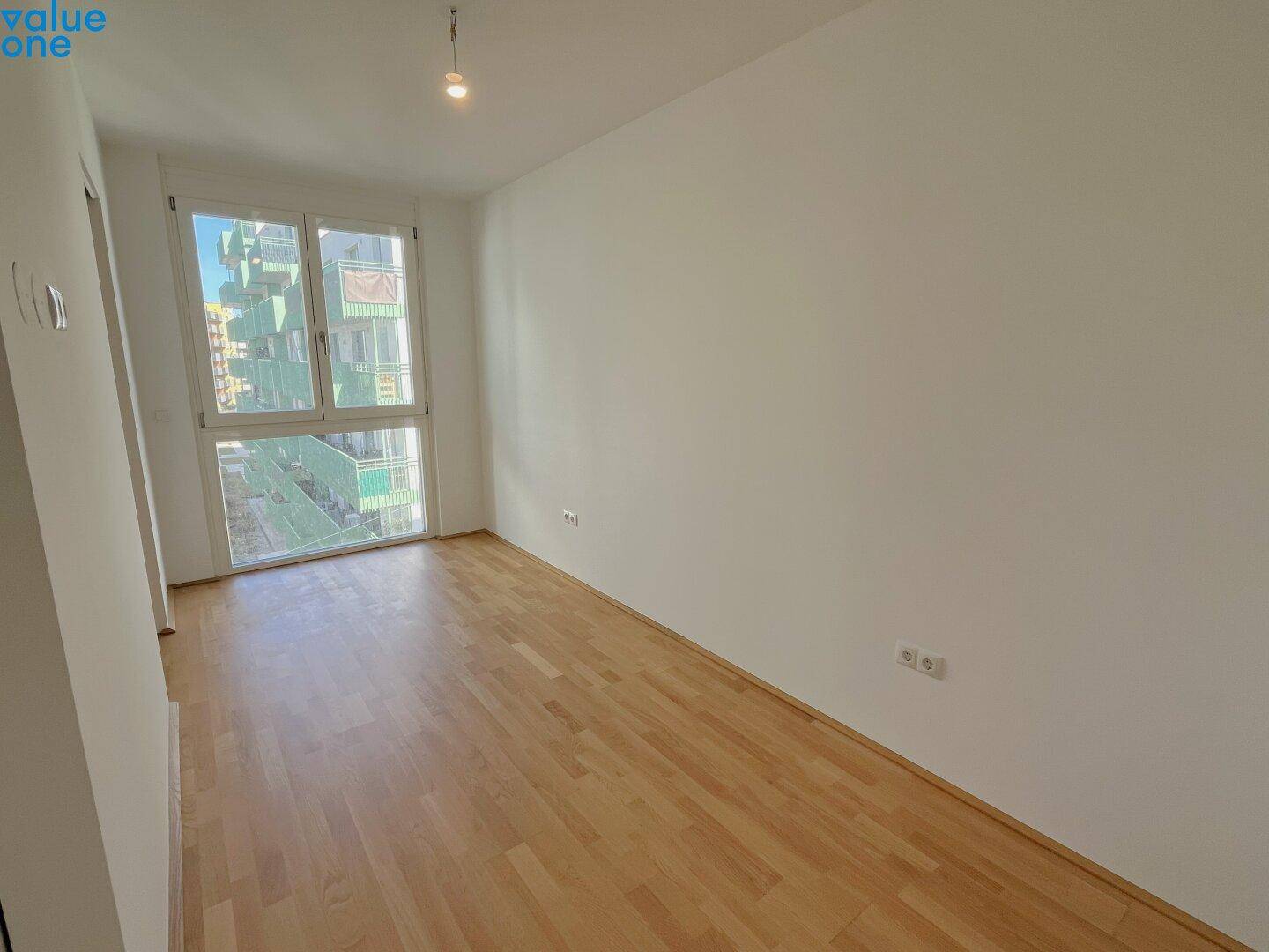 Heller Raum mit großem Fenster und Parkettboden, ideal für verschiedene Nutzungen.