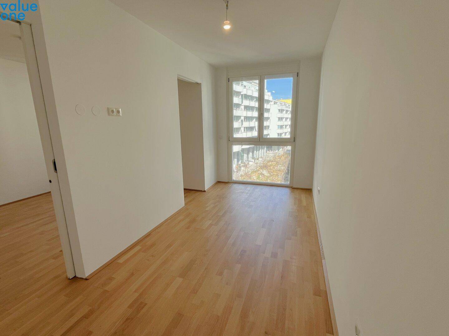 Leerer Raum mit viel Tageslicht und Blick auf die umliegenden Gebäude.