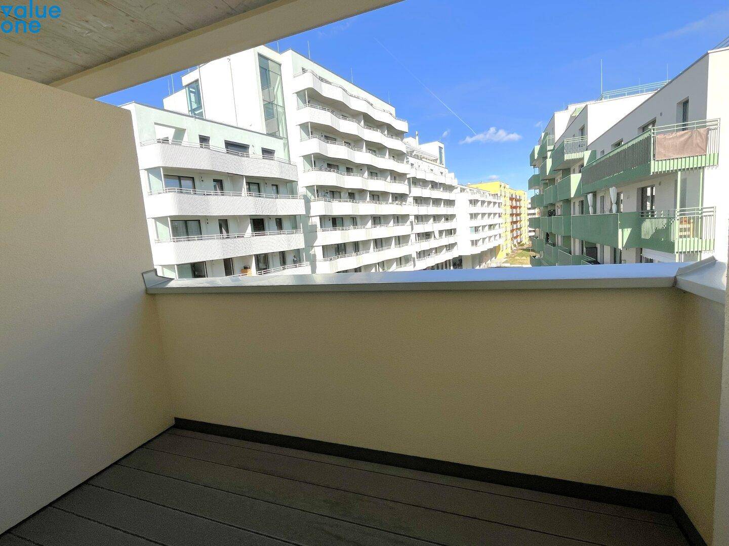 Leerer Balkon mit Holzboden und freiem Blick auf die umliegenden Gebäude.