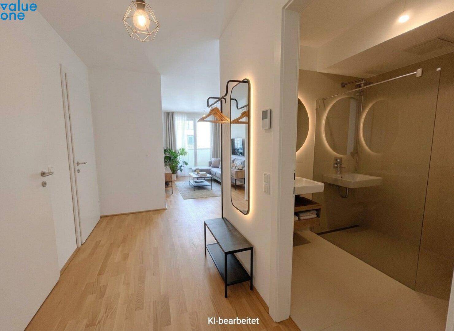 Heller Flur mit Garderobe und beleuchtetem Spiegel, der zum Wohnbereich und Badezimmer führt.