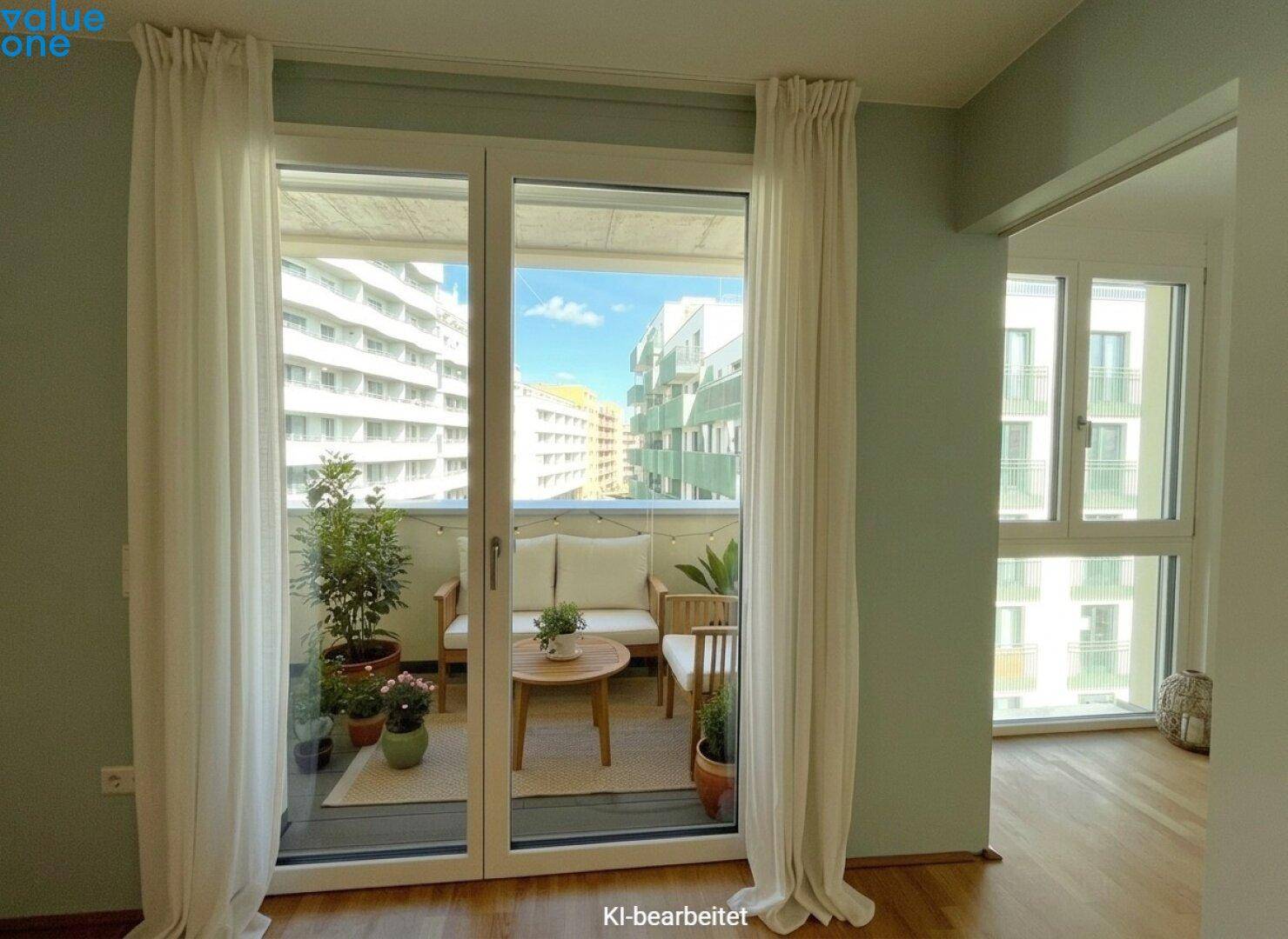 Heller Innenraum mit großen Fenstern, die den Blick auf einen möblierten Balkon und umliegende Gebäude freigeben.