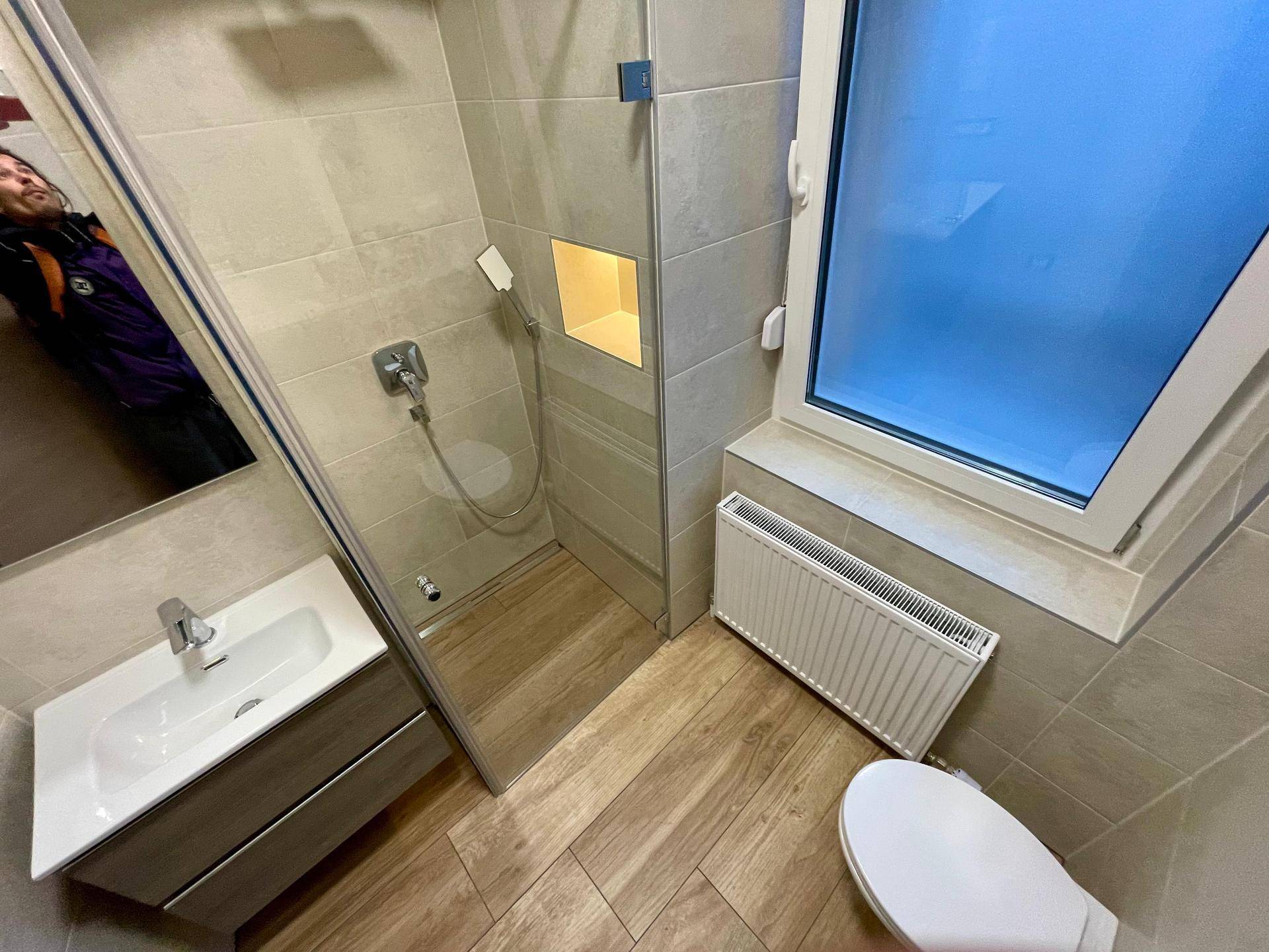 Helles Badezimmer mit moderner Dusche, WC und Waschbecken, ausgestattet mit Fenster.