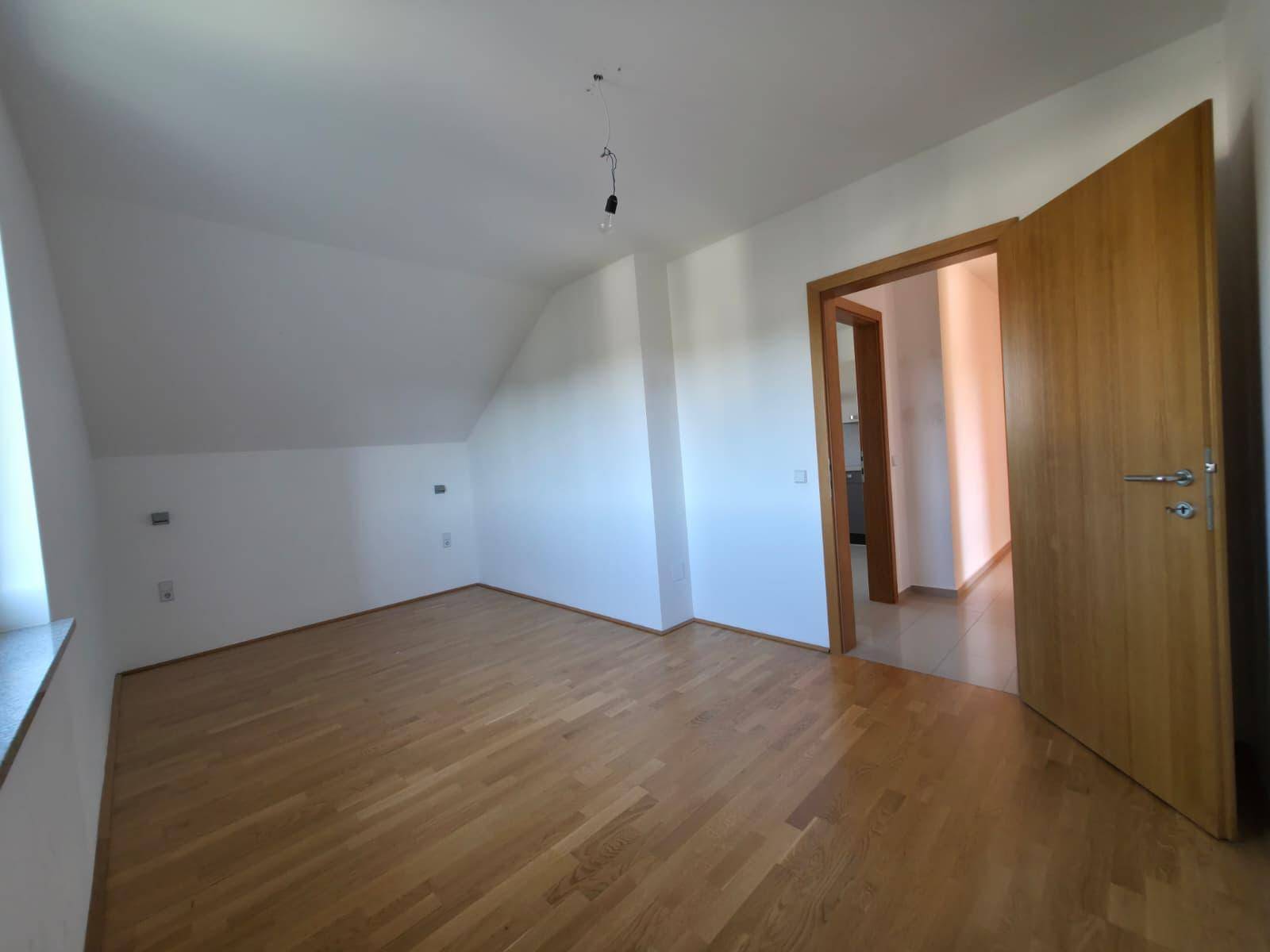 Geräumiges Zimmer mit hellem Holzparkettboden und Zugang zu weiteren Räumen.