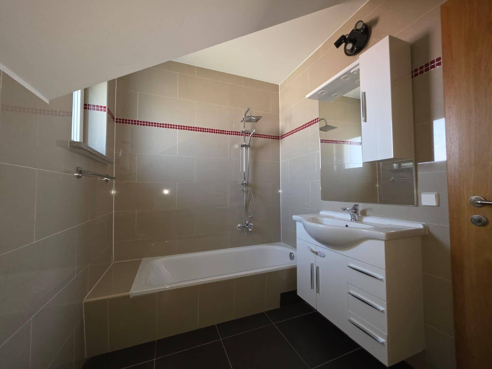 Modernes Badezimmer mit Badewanne, Waschtisch und beheiztem Handtuchhalter.